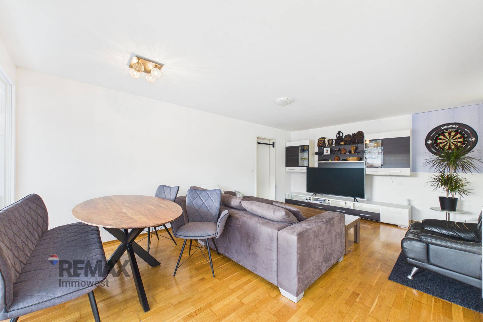 Gemütlicher Wohn-Essbereich mit Holzboden, Sofa und modernem Esstisch mit Stühlen.
