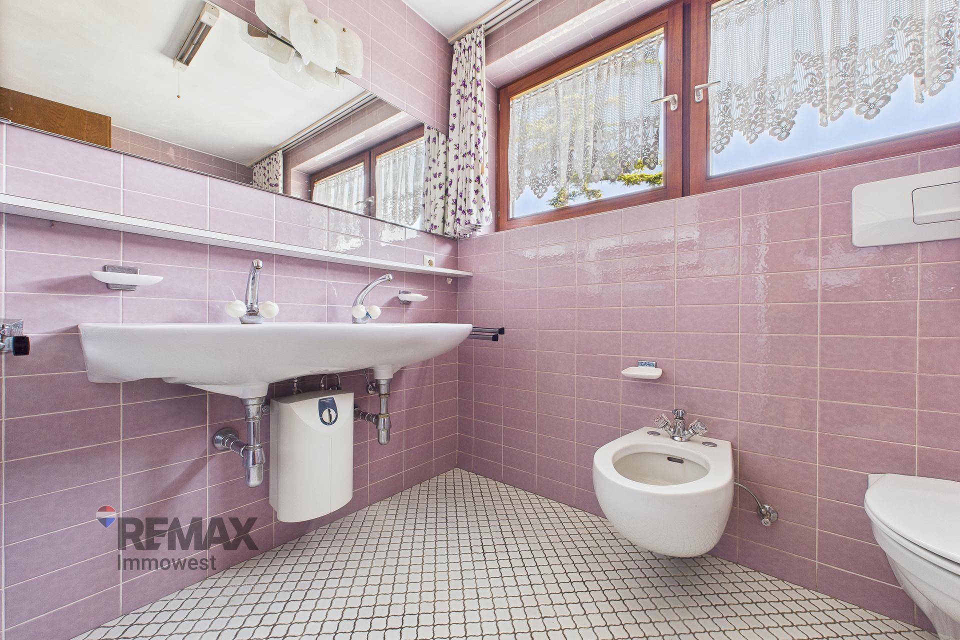 Badezimmer im 80er-Jahre-Stil mit rosa Fliesen, Doppelwaschbecken und Bidet.