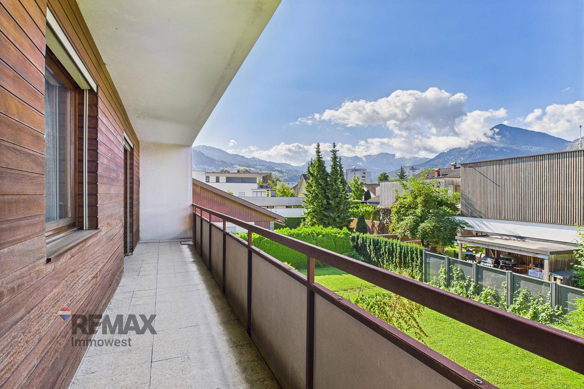 Langer Balkon mit Bergblick, Holzwandverkleidung und Metallgeländer.
