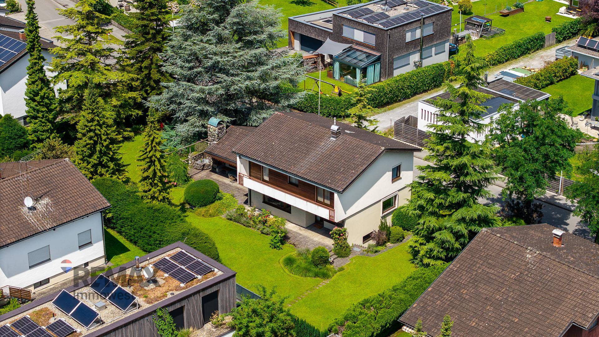 Luftaufnahme eines Einfamilienhauses mit großem Garten in einer Wohnsiedlung.