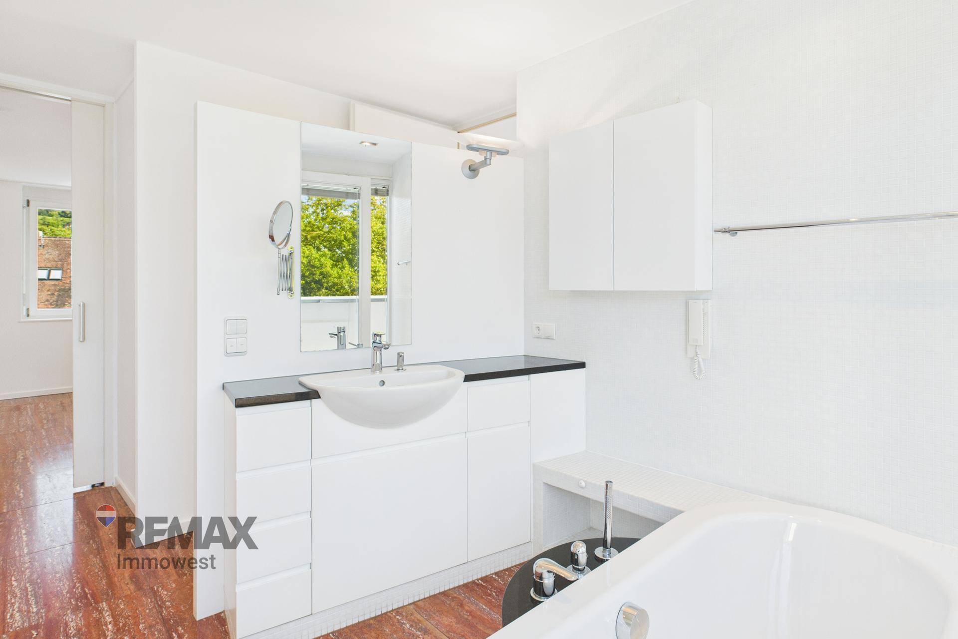 Modernes Badezimmer mit Einzelwaschbecken, Spiegelschrank und Badewanne.