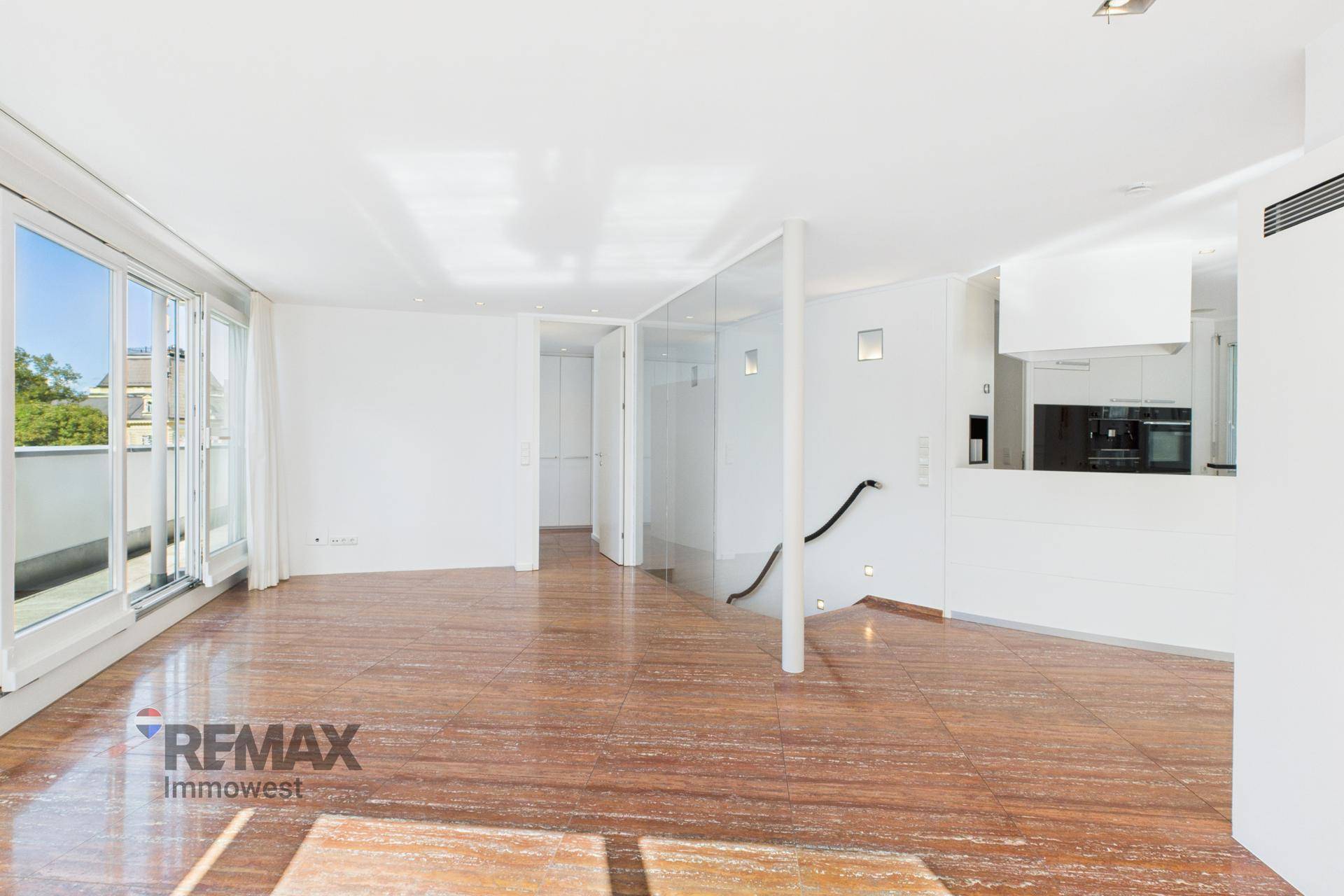 Geräumiger Wohnbereich mit Steinboden, minimalistischem Design und Zugang zu einer Treppe.