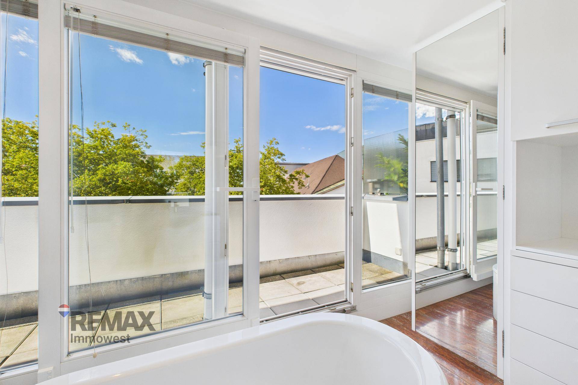 Badezimmer mit großen Fensterfronten, die viel Licht hereinlassen und einen Blick auf die Terrasse bieten.