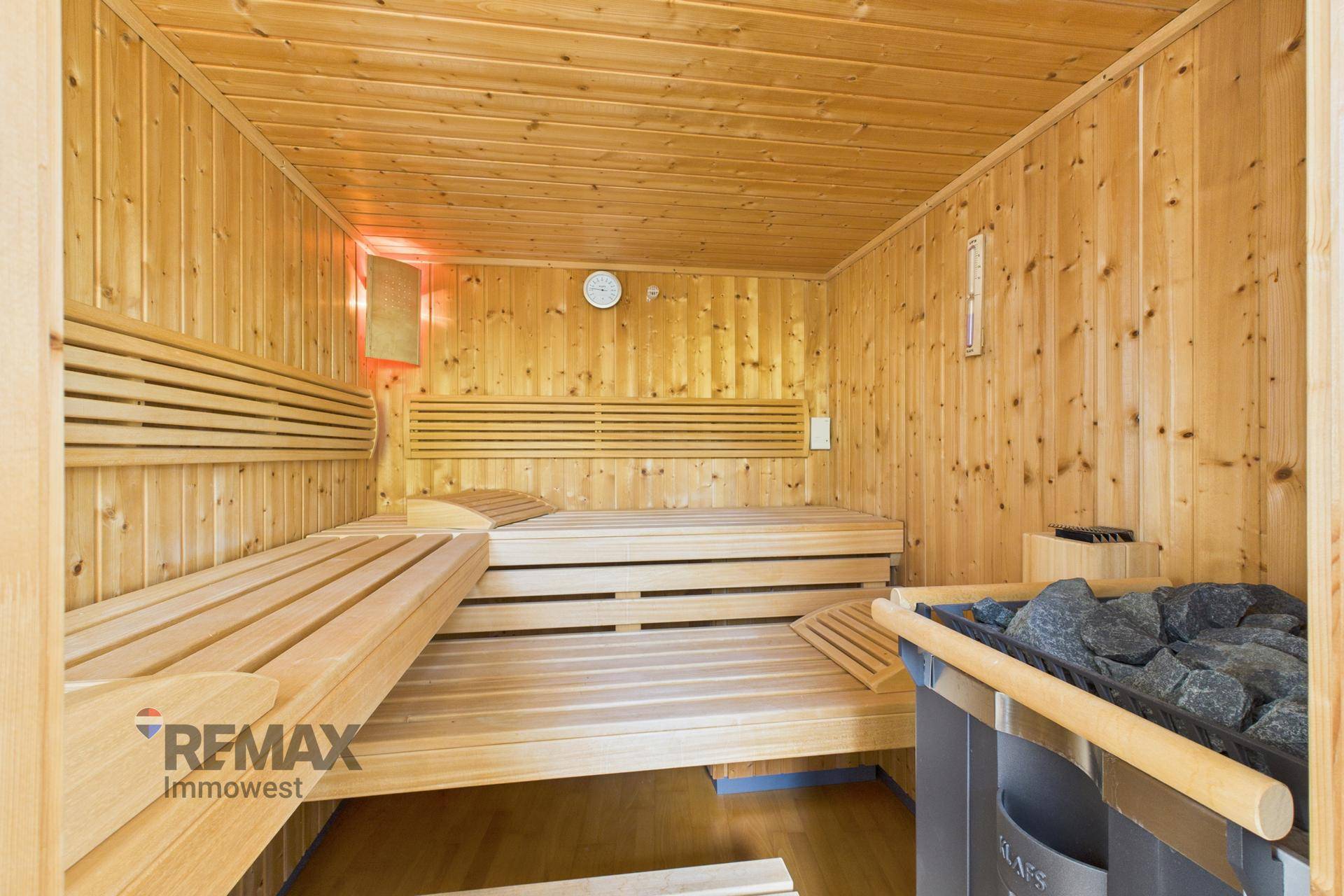 Geräumige Holzsauna mit mehreren Bänken und einem Saunaofen für entspannende Momente.