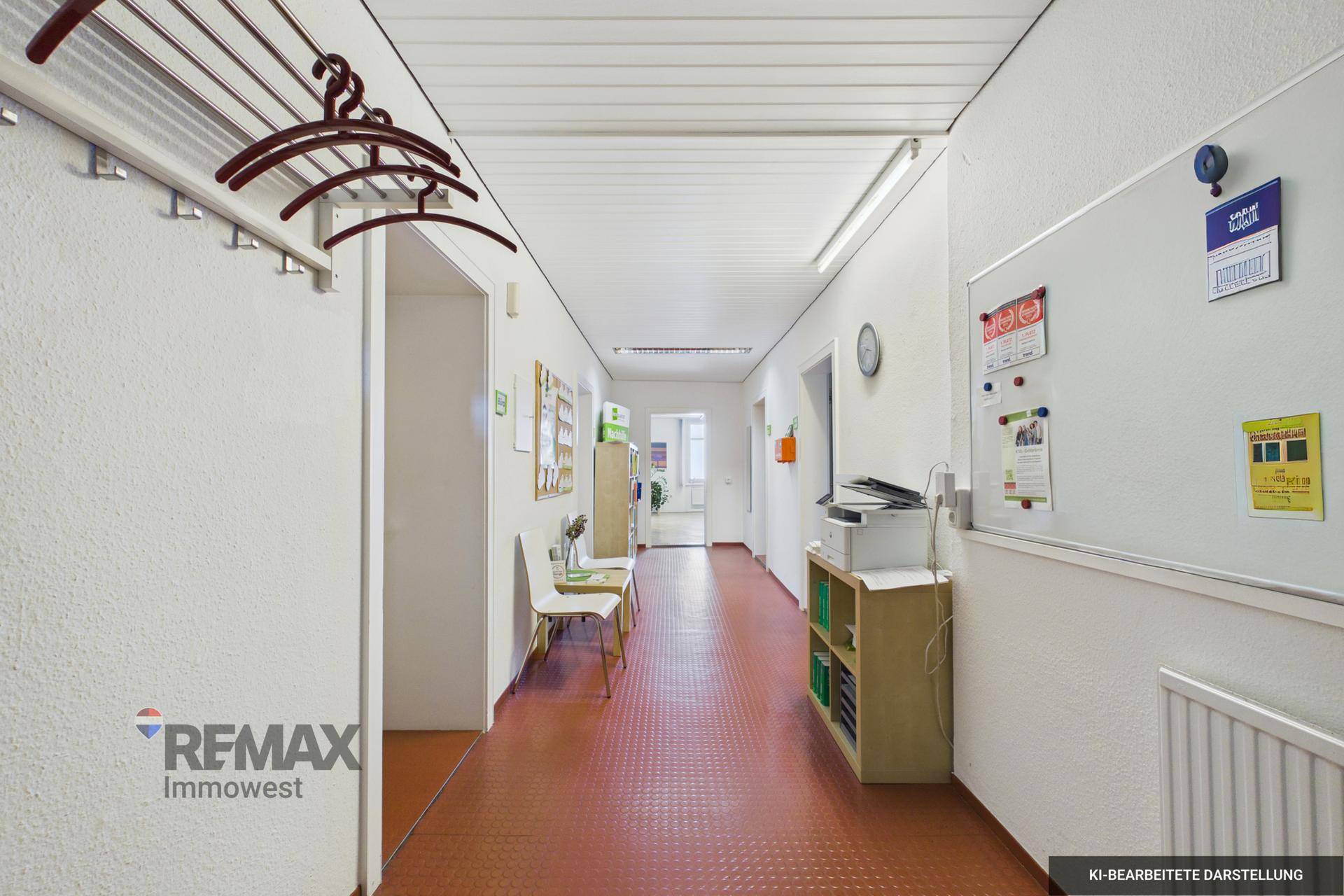 Langer, schmaler Flur mit rotem Bodenbelag und Garderobe, ideal für Büroräume oder Praxen.
