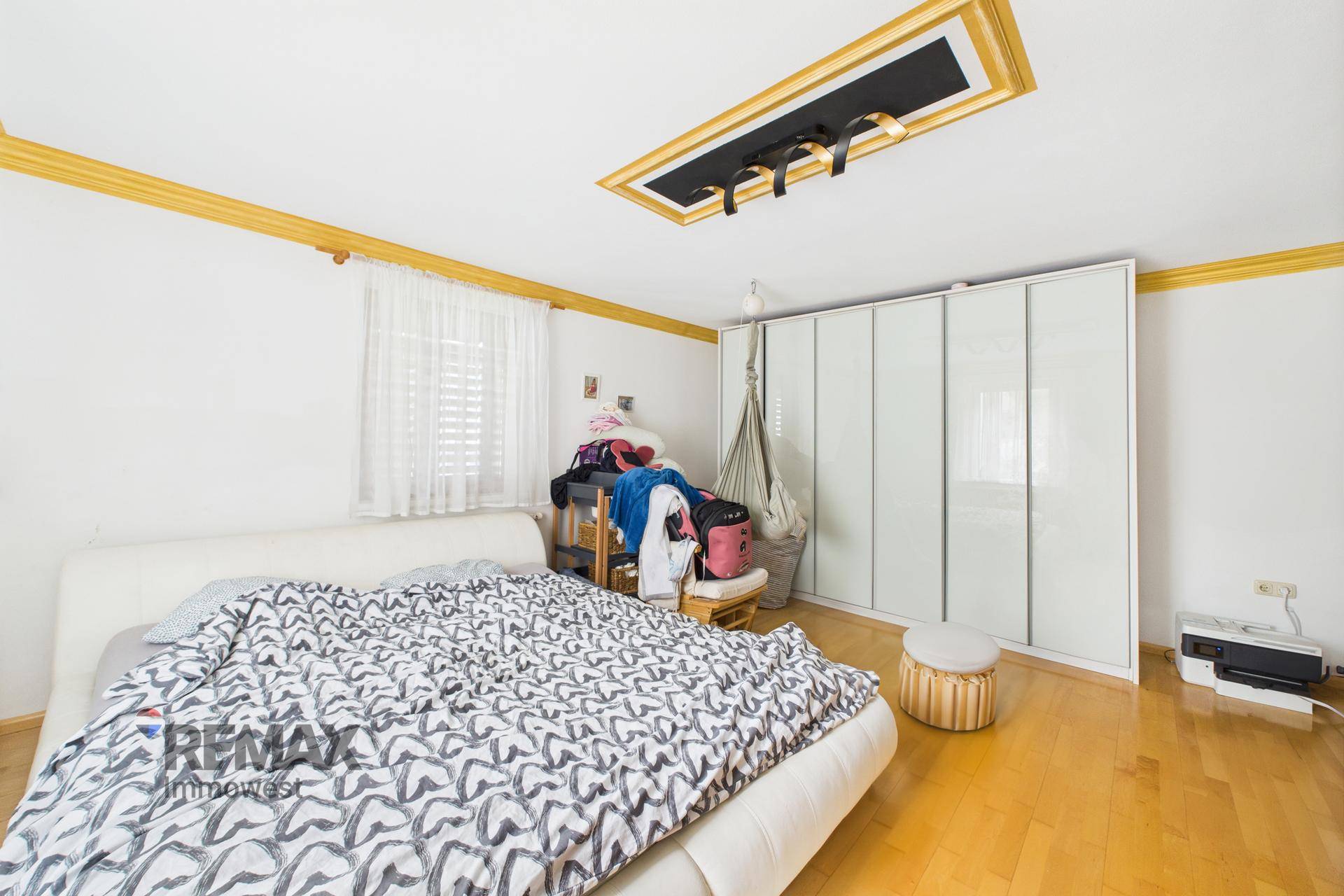 Schlafzimmer mit Doppelbett, großem Kleiderschrank und dekorativer Deckenbeleuchtung.
