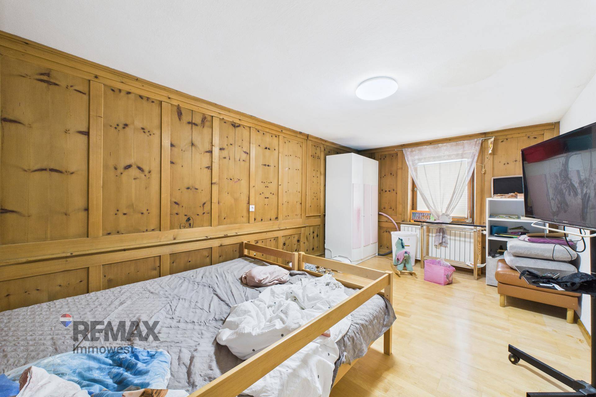 Schlafzimmer mit rustikalen Holzvertäfelungen an den Wänden und hellem Holzboden.