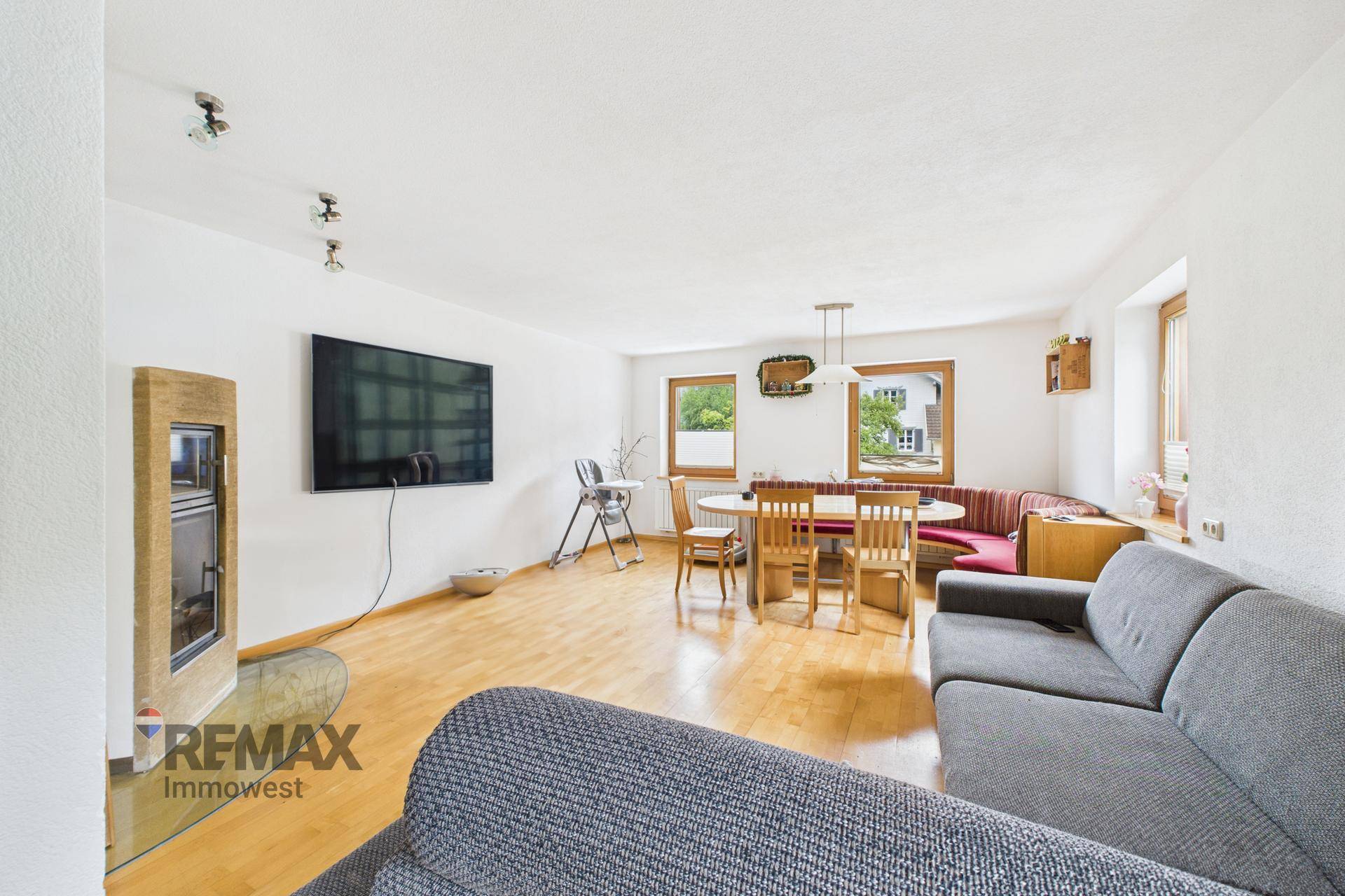 Geräumiger Wohn-Essbereich mit Holzboden, gemütlichem Sofa und modernem Kaminofen.