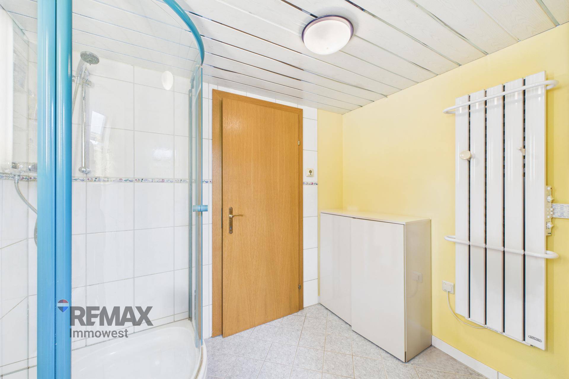 Badezimmer mit Duschkabine, weißen Fliesen und gelb gestrichenen Wänden.