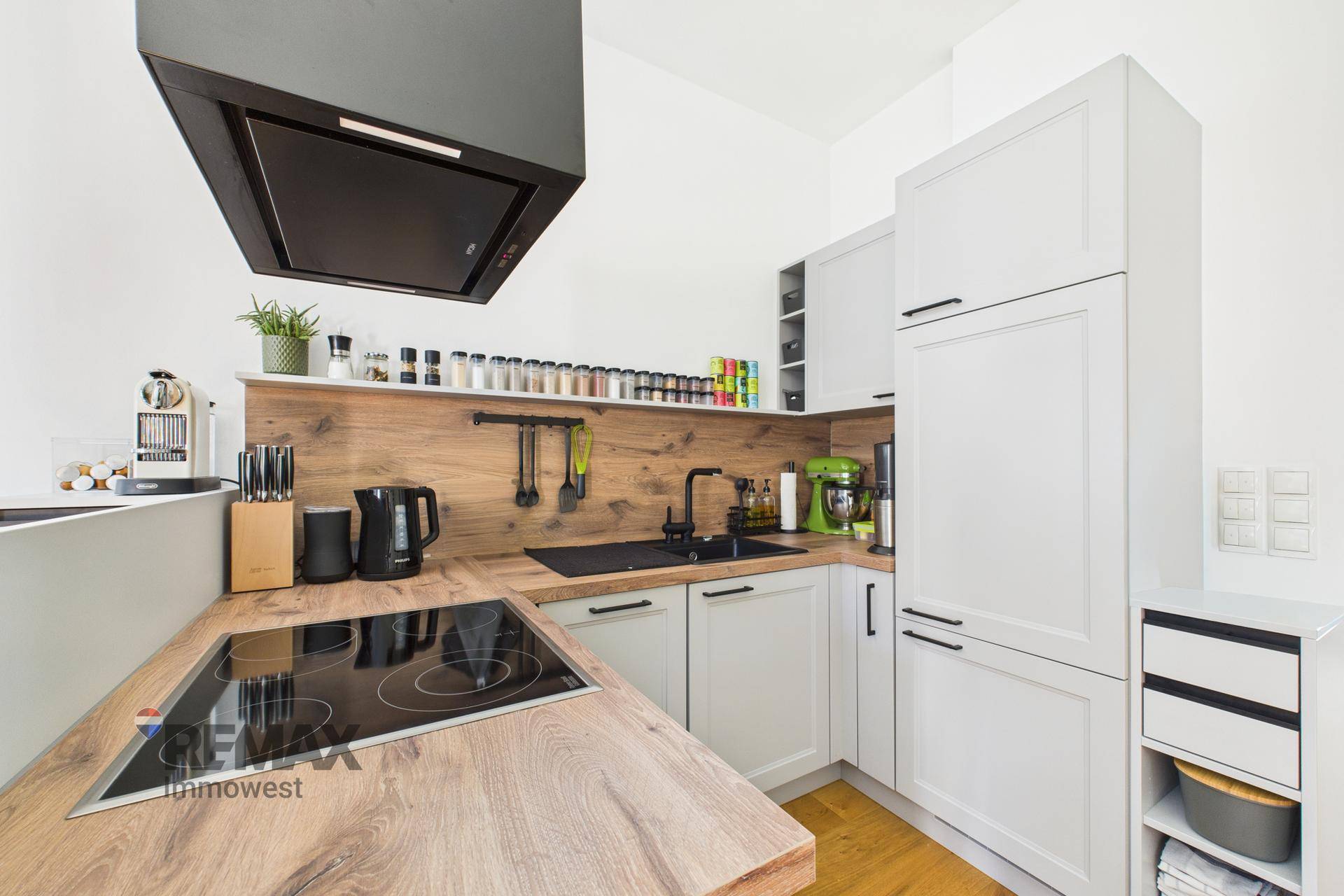 Helle Einbauküche mit Holzdetails, Induktionskochfeld und modernen Geräten, sehr gepflegt.