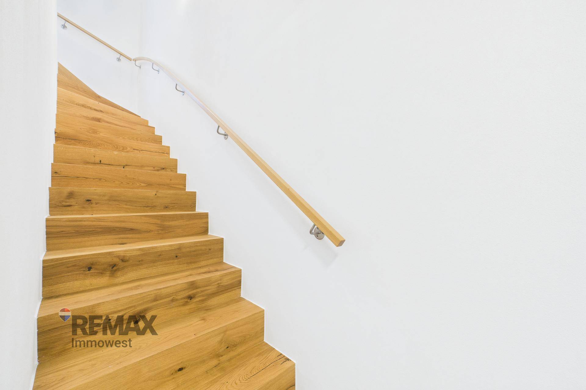 Moderne Holztreppe mit schlichtem Geländer, die verschiedene Ebenen des Hauses verbindet.