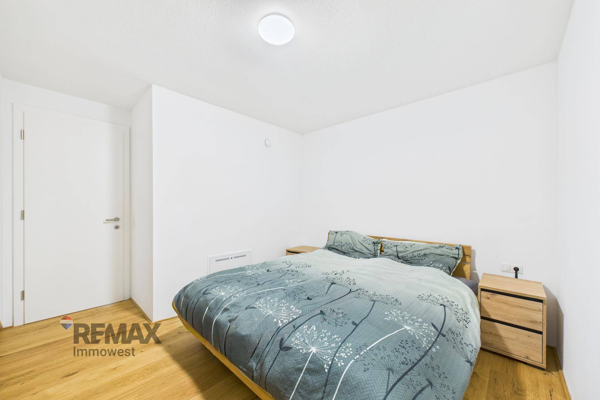 Gemütliches Schlafzimmer mit Doppelbett und Holzboden, schlicht und funktional eingerichtet.