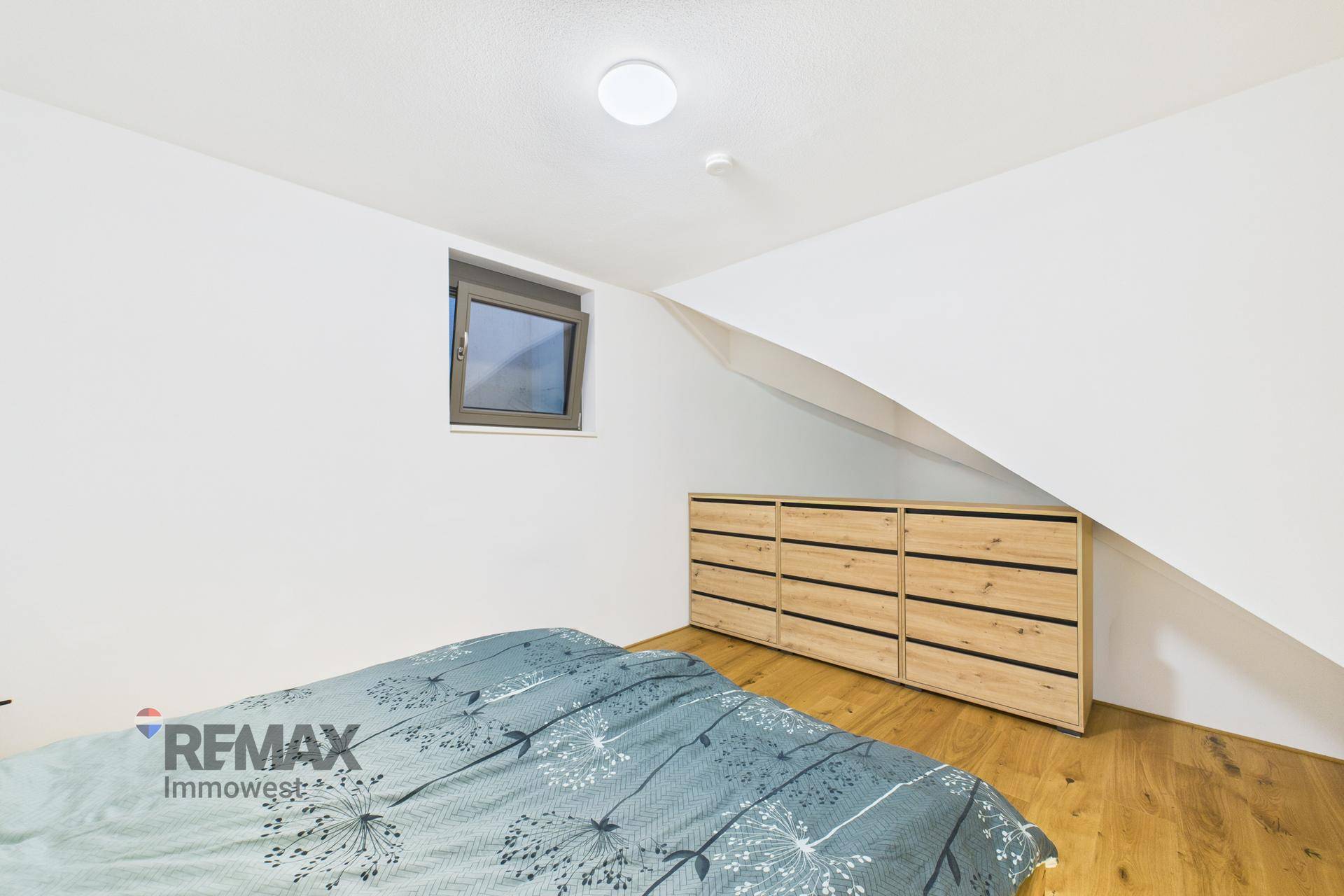 Schlafzimmer im Dachgeschoss mit schräger Decke, Holzboden und integrierten Kommoden.