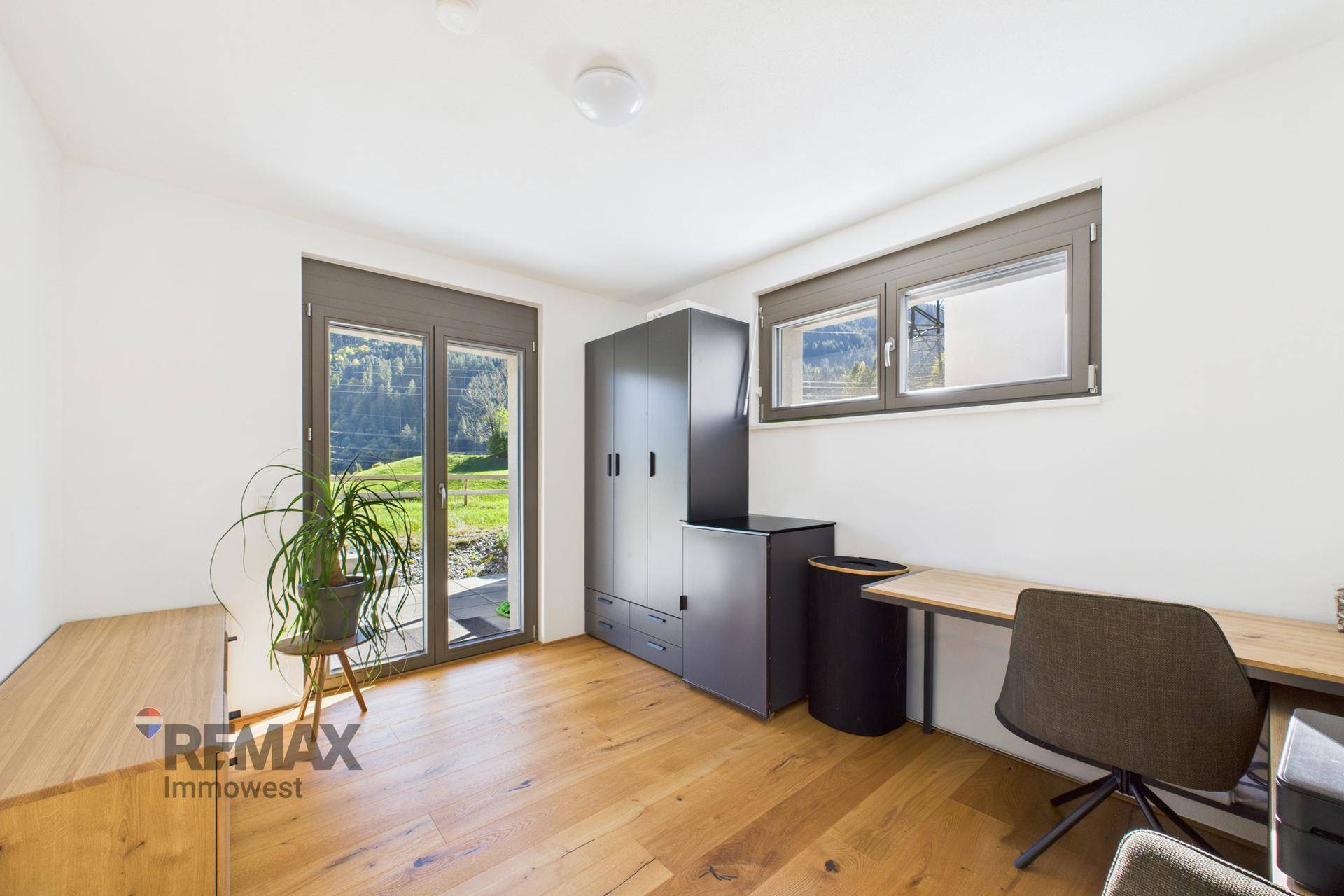Heller Raum mit Holzboden, Schreibtisch und Zugang zur Terrasse, ideal als Büro oder Schlafzimmer.