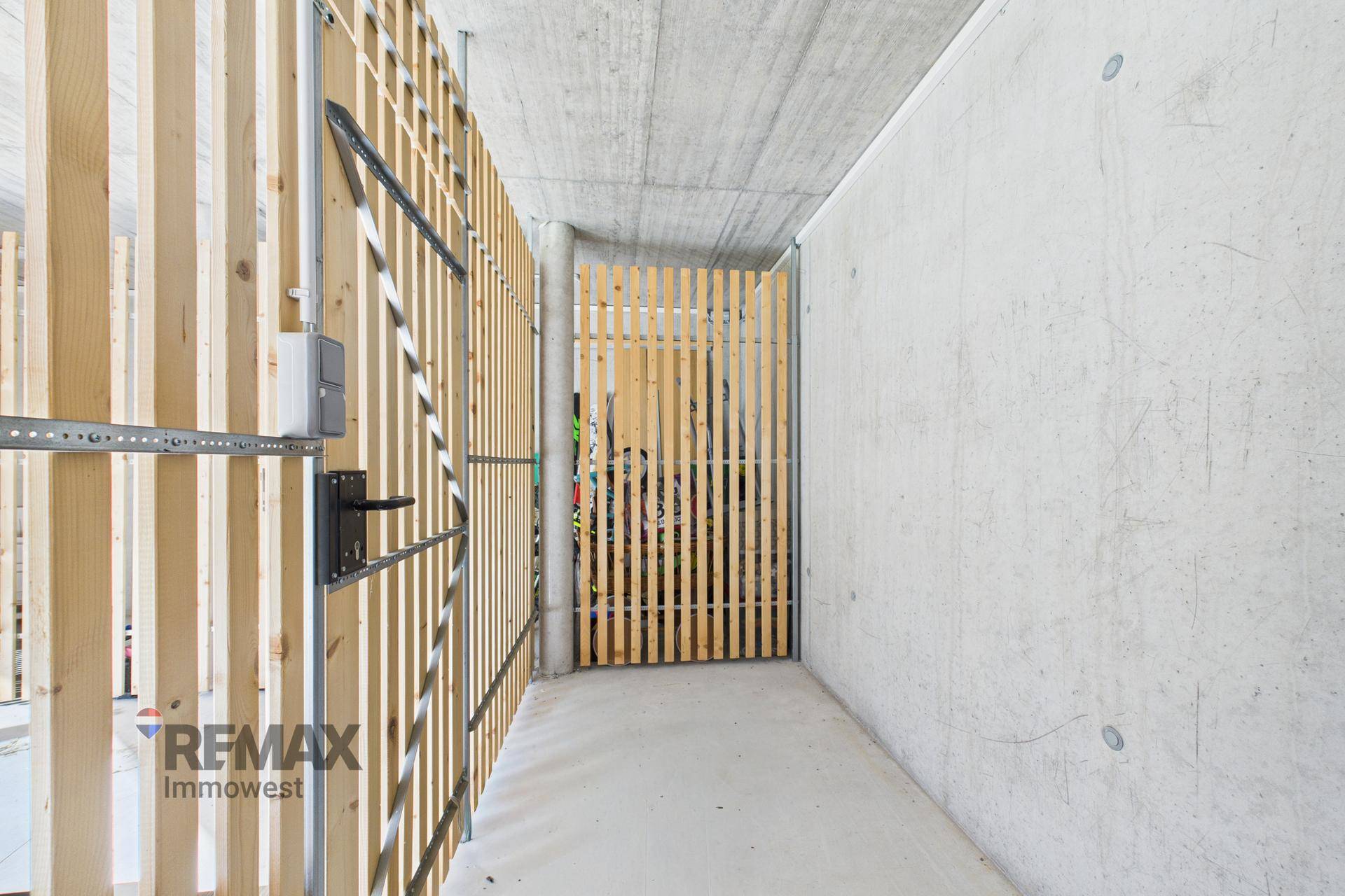 Praktischer Abstellraum mit Holzlattenwänden und Betonboden, ideal für zusätzlichen Stauraum.