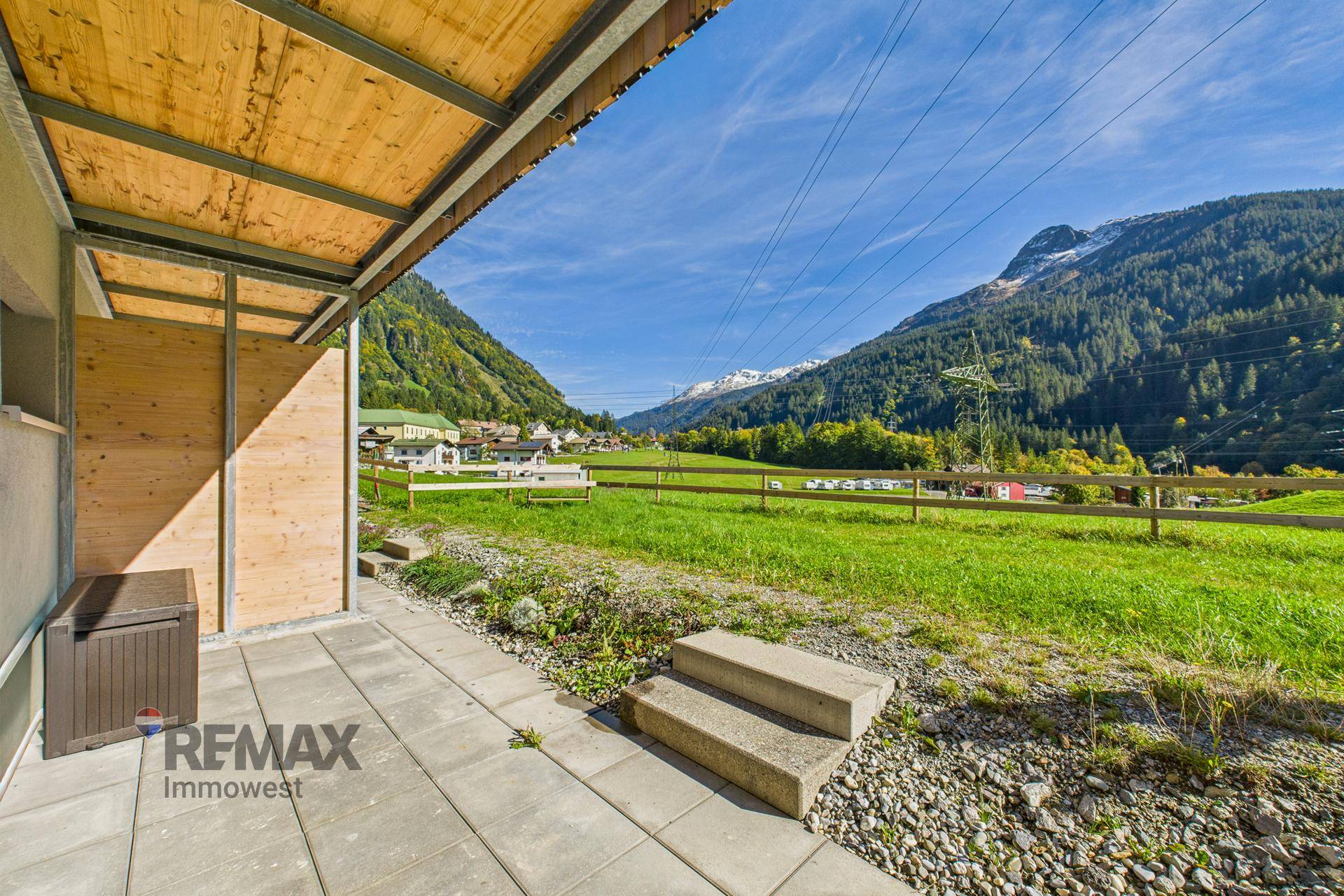 Geräumige Terrasse mit Blick auf weite grüne Felder und die umliegende Berglandschaft.