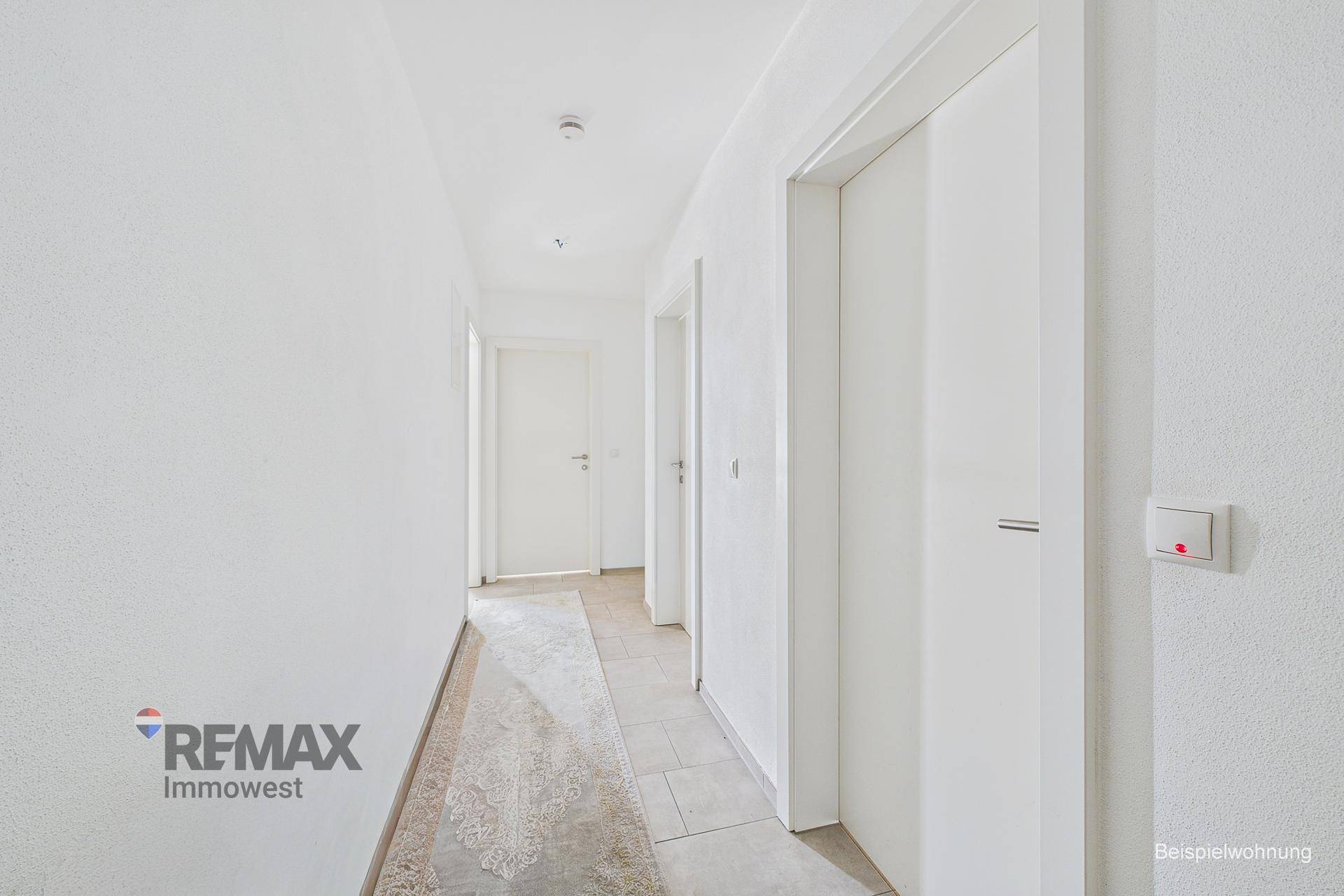 Langer, heller Flur mit Fliesenboden und weißen Türen in der Wohnung.