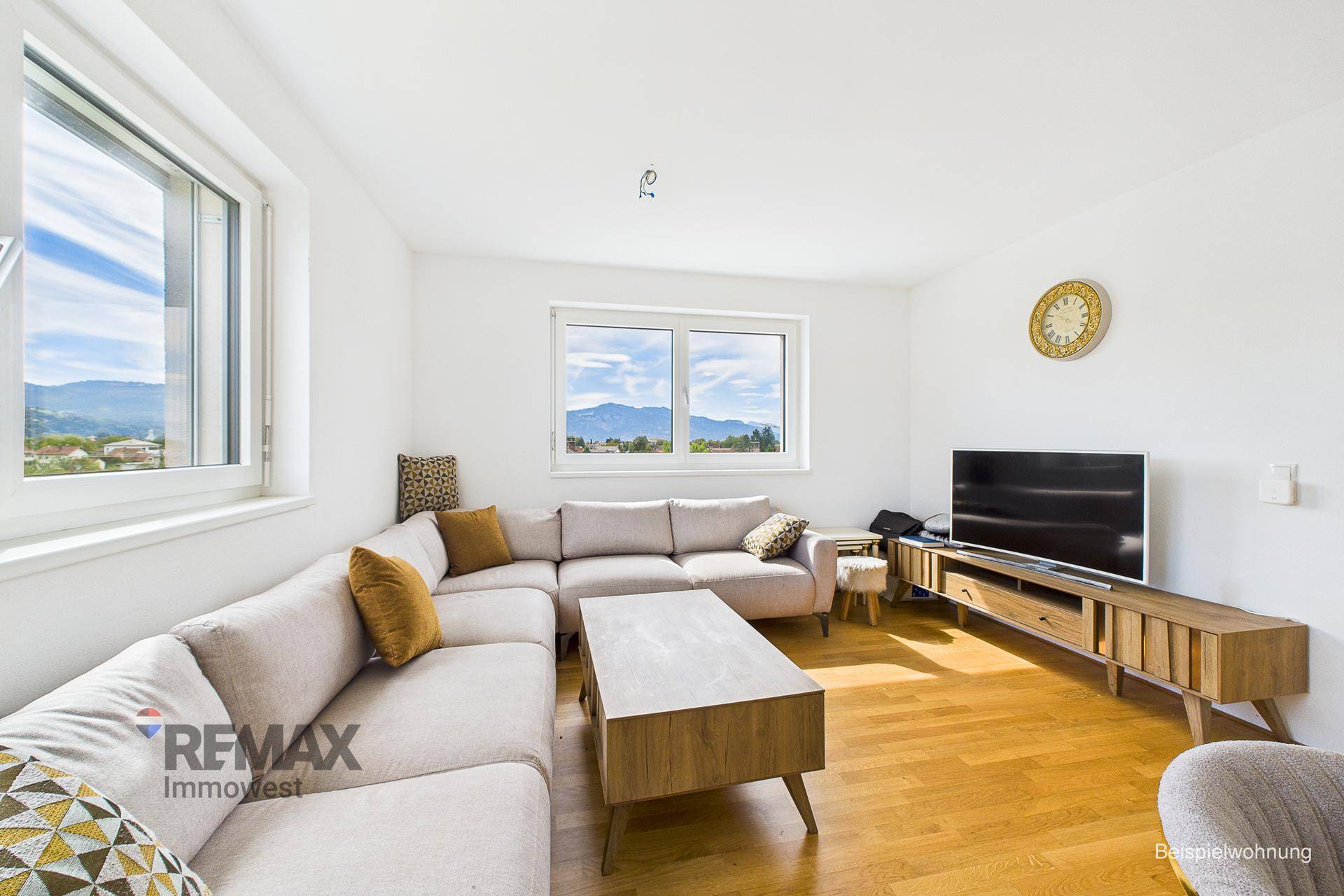 Helles Wohnzimmer mit großem Ecksofa, Holzboden und Blick auf die Berge.