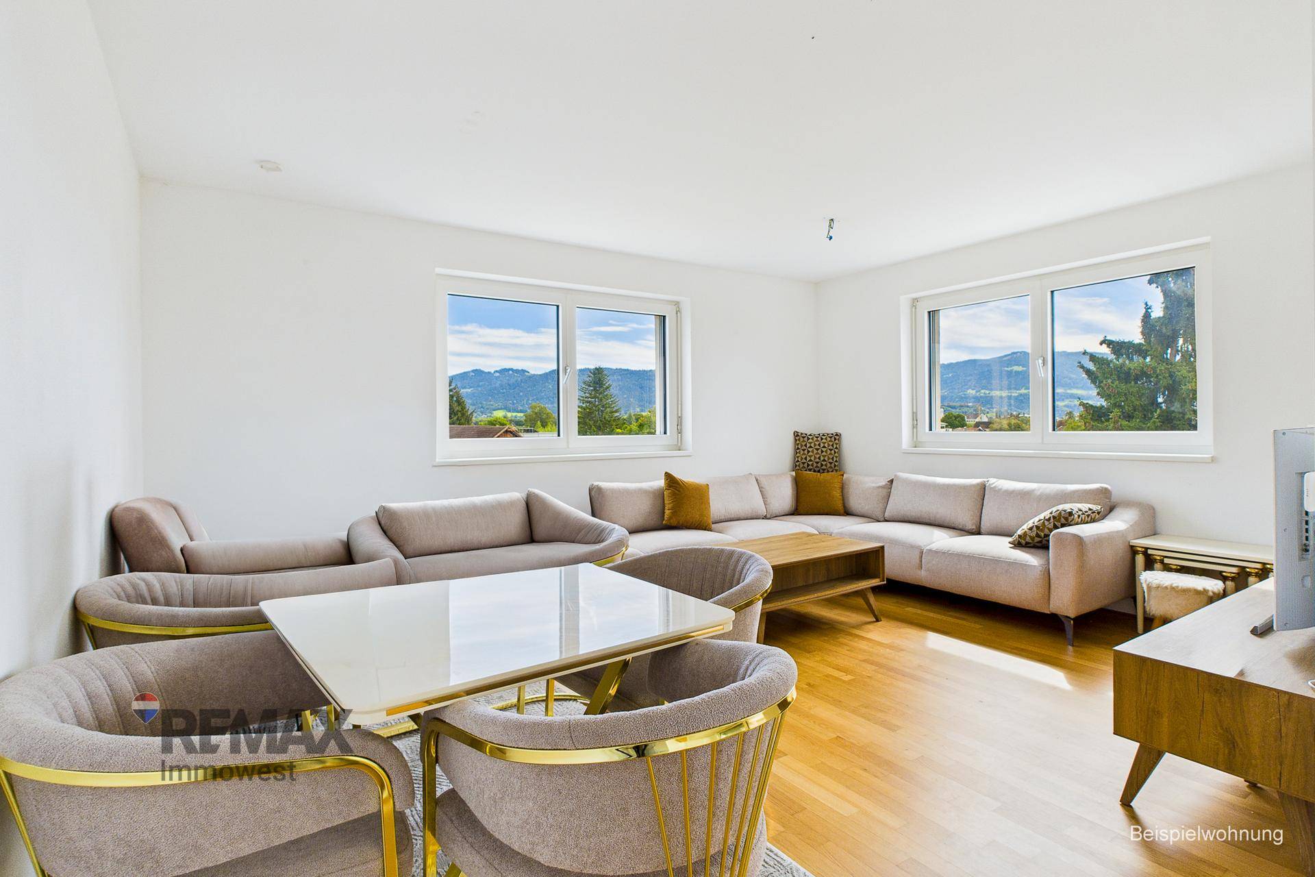 Geräumiges Wohnzimmer mit Holzboden, bequemen Sofas und Bergblick durch große Fenster.