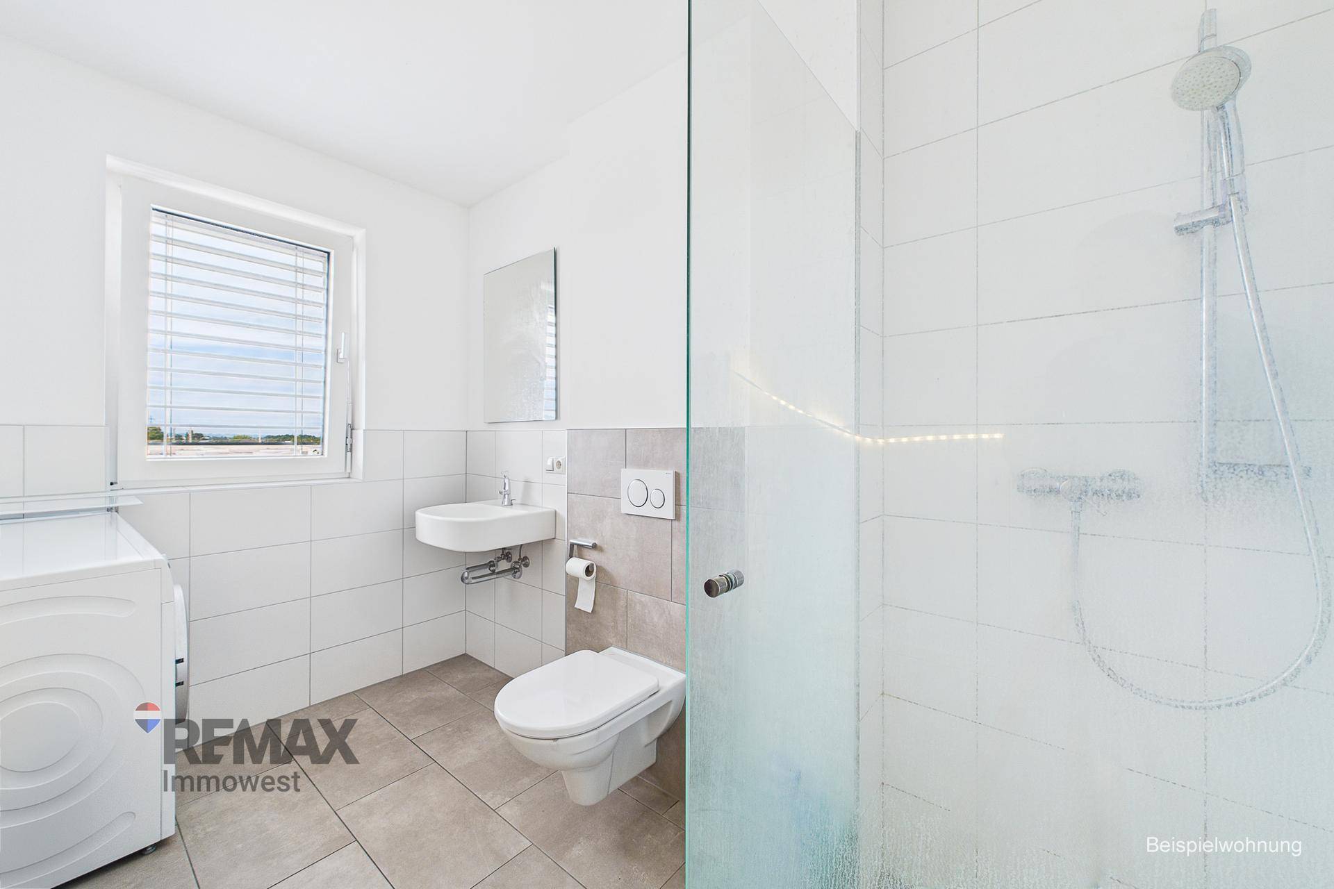 Modernes Badezimmer mit Dusche, Waschbecken, WC und Waschmaschine.