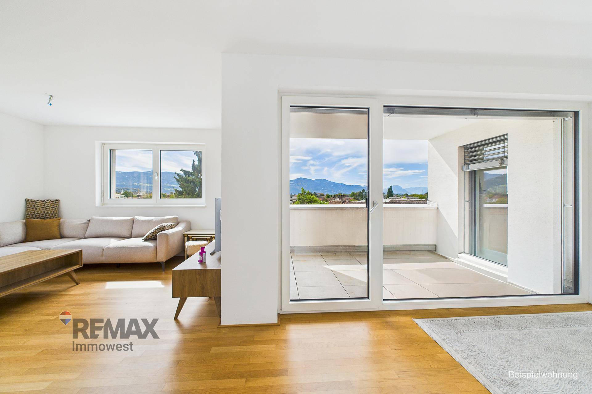 Wohnzimmer mit Holzboden, Zugang zum Balkon und weitem Blick auf die Landschaft.