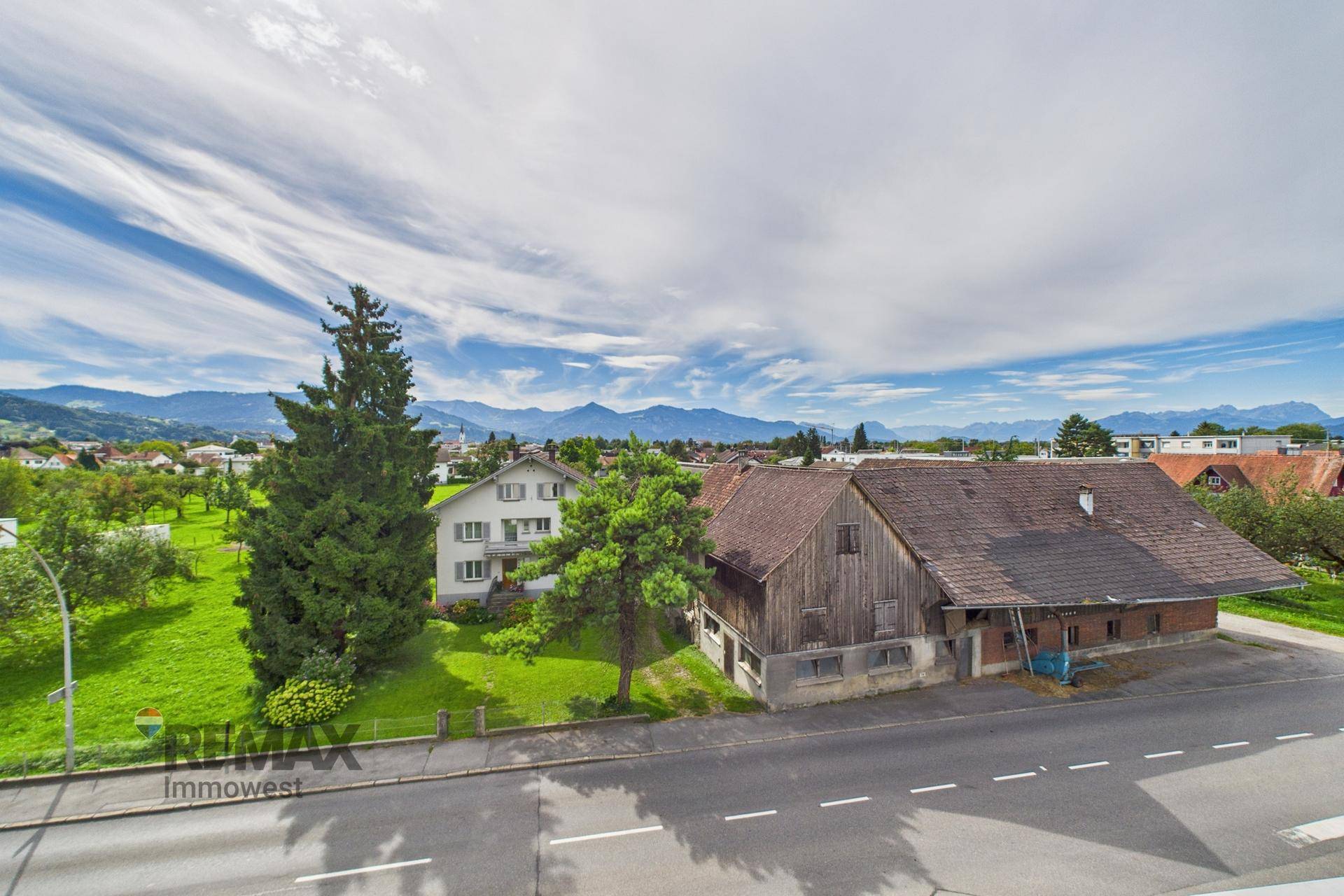 Weitläufiger Blick auf die umliegende Landschaft mit Bergen und ländlichen Gebäuden.