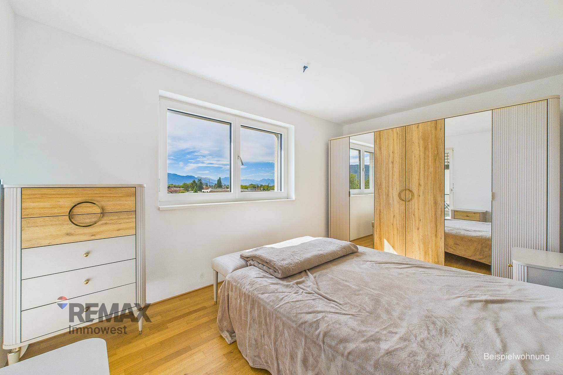 Helles Schlafzimmer mit Holzboden, modernem Kleiderschrank und Bergblick.