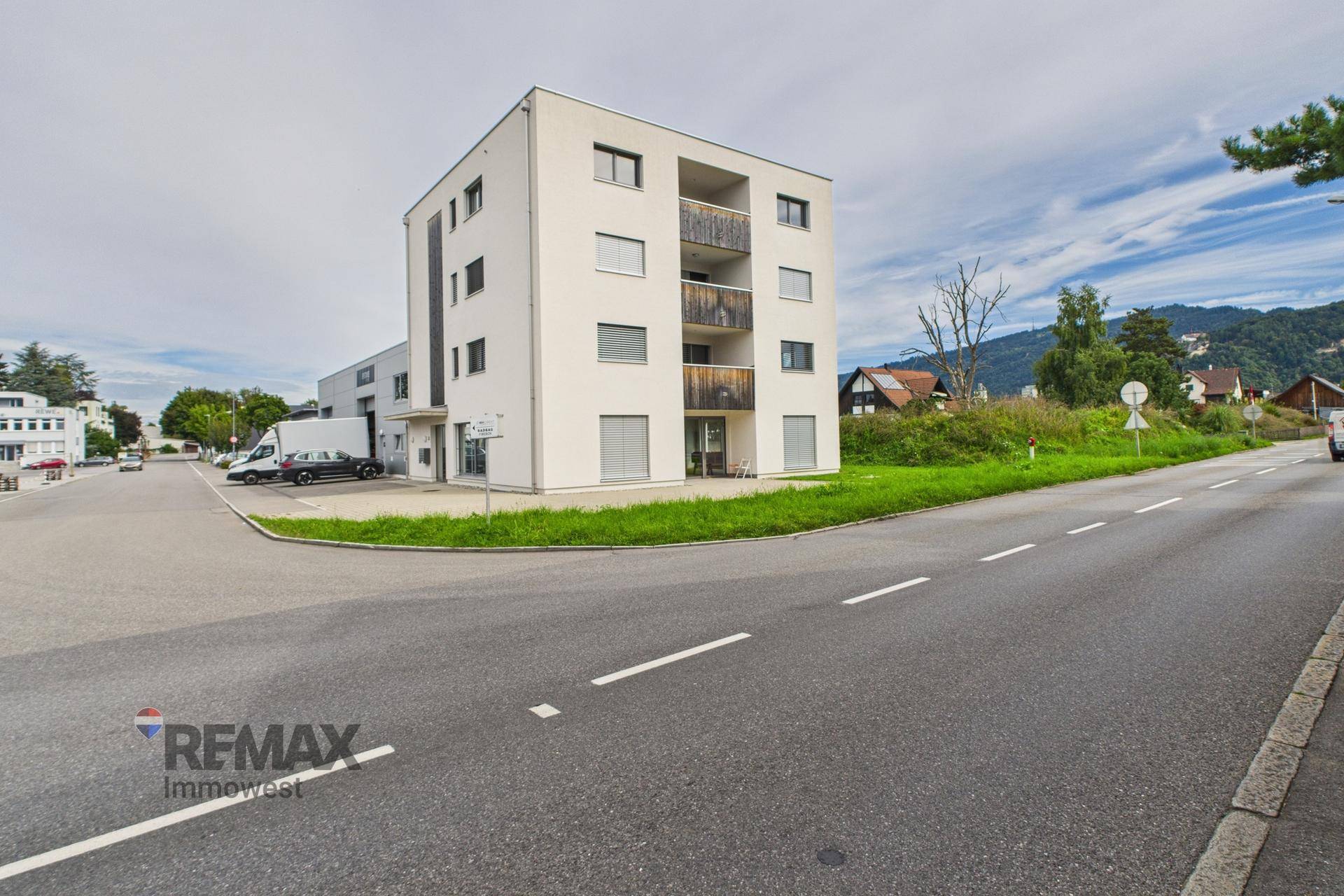 Modernes Wohngebäude mit weißer Fassade und Balkonen an einer Straße gelegen.