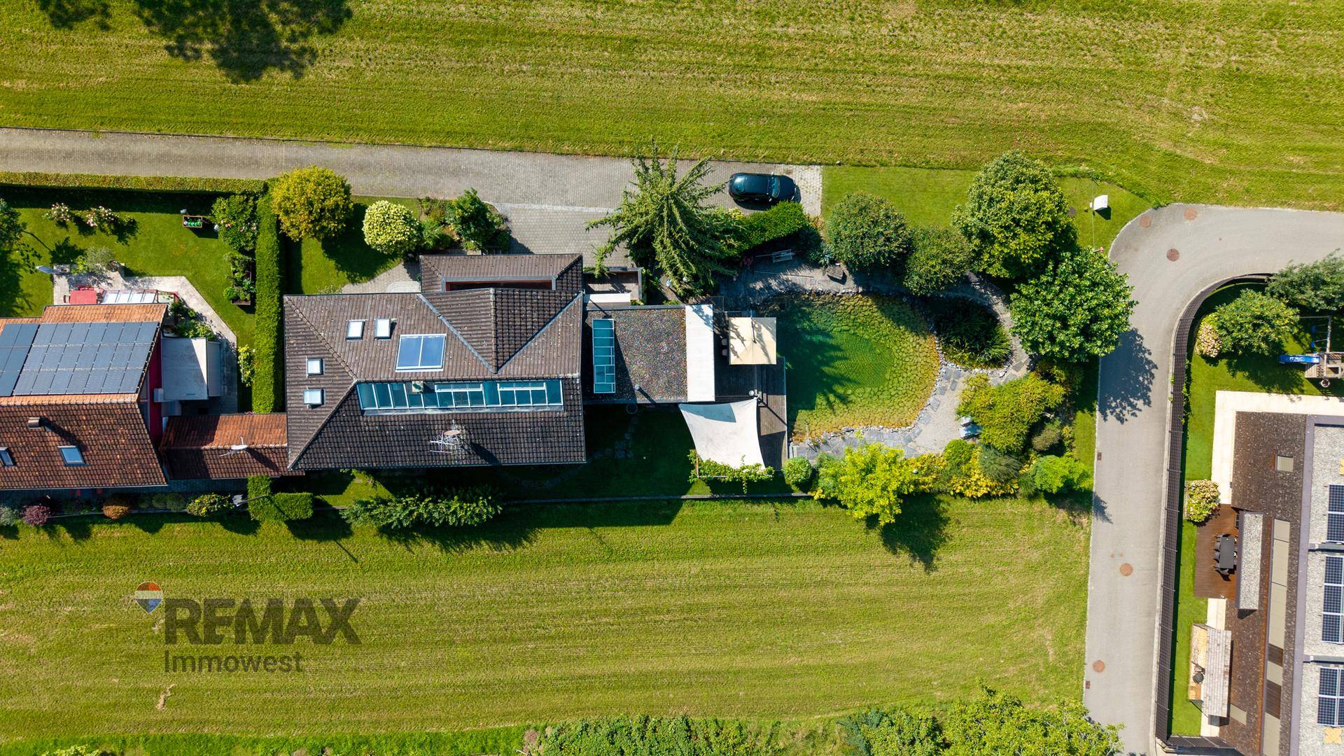 Vogelperspektive des Anwesens mit Wohnhaus, Naturteich und weitläufigen Grünflächen in ländlicher Umgebung.