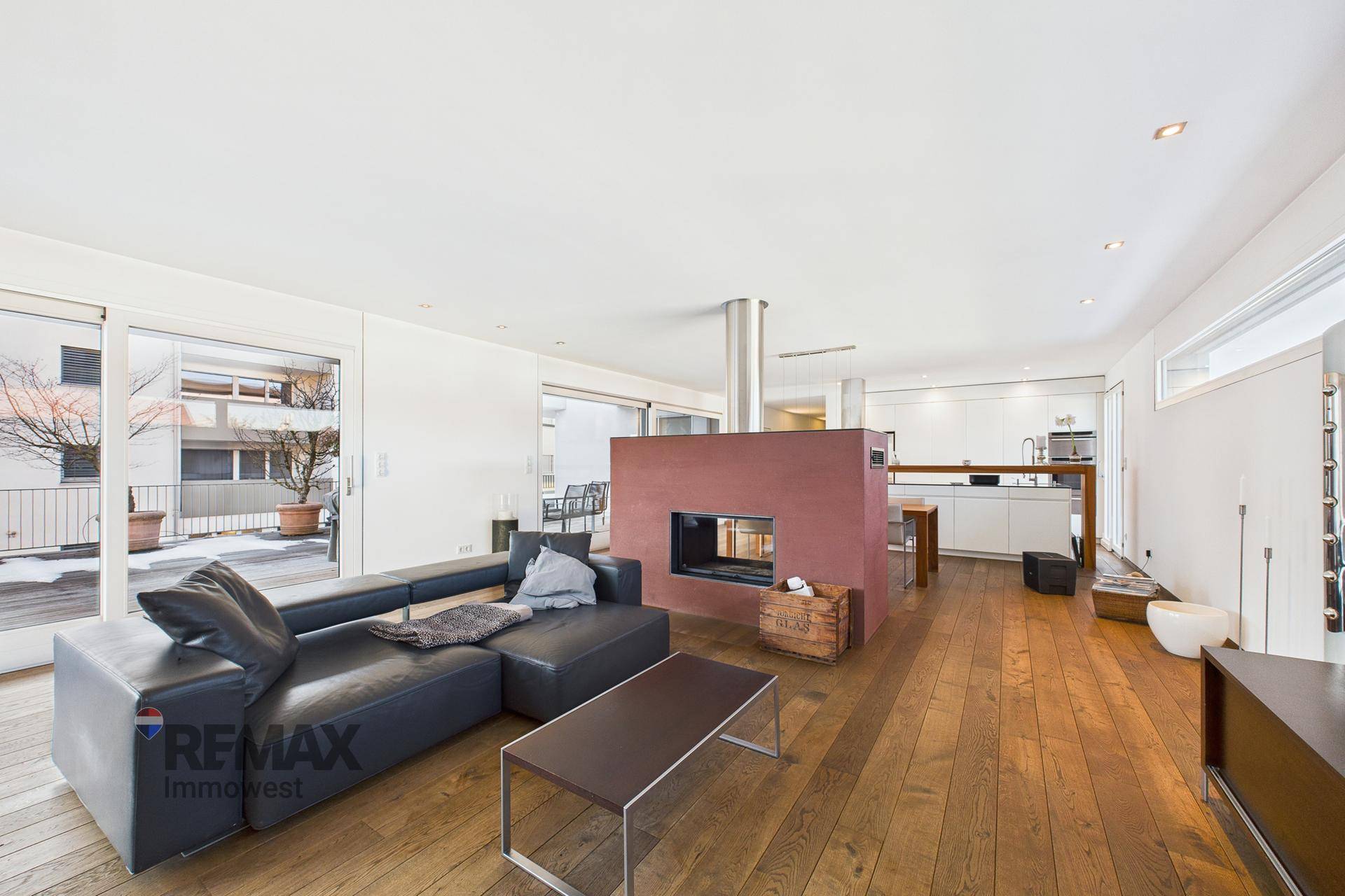 Geräumiger Wohnbereich mit großem Sofa, Kamin und Zugang zur Außenterrasse.