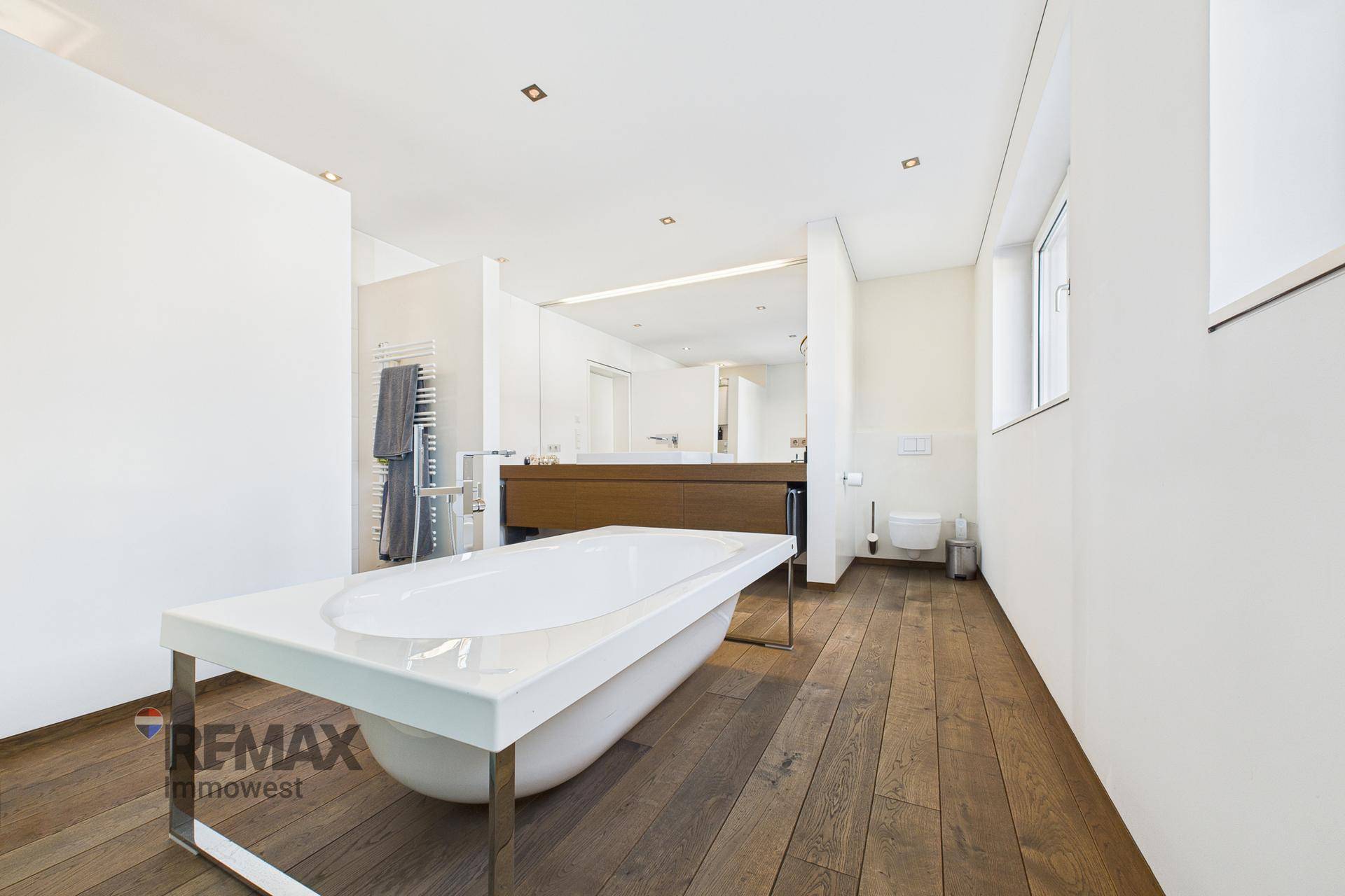 Modernes Badezimmer mit freistehender Badewanne und Holzboden.