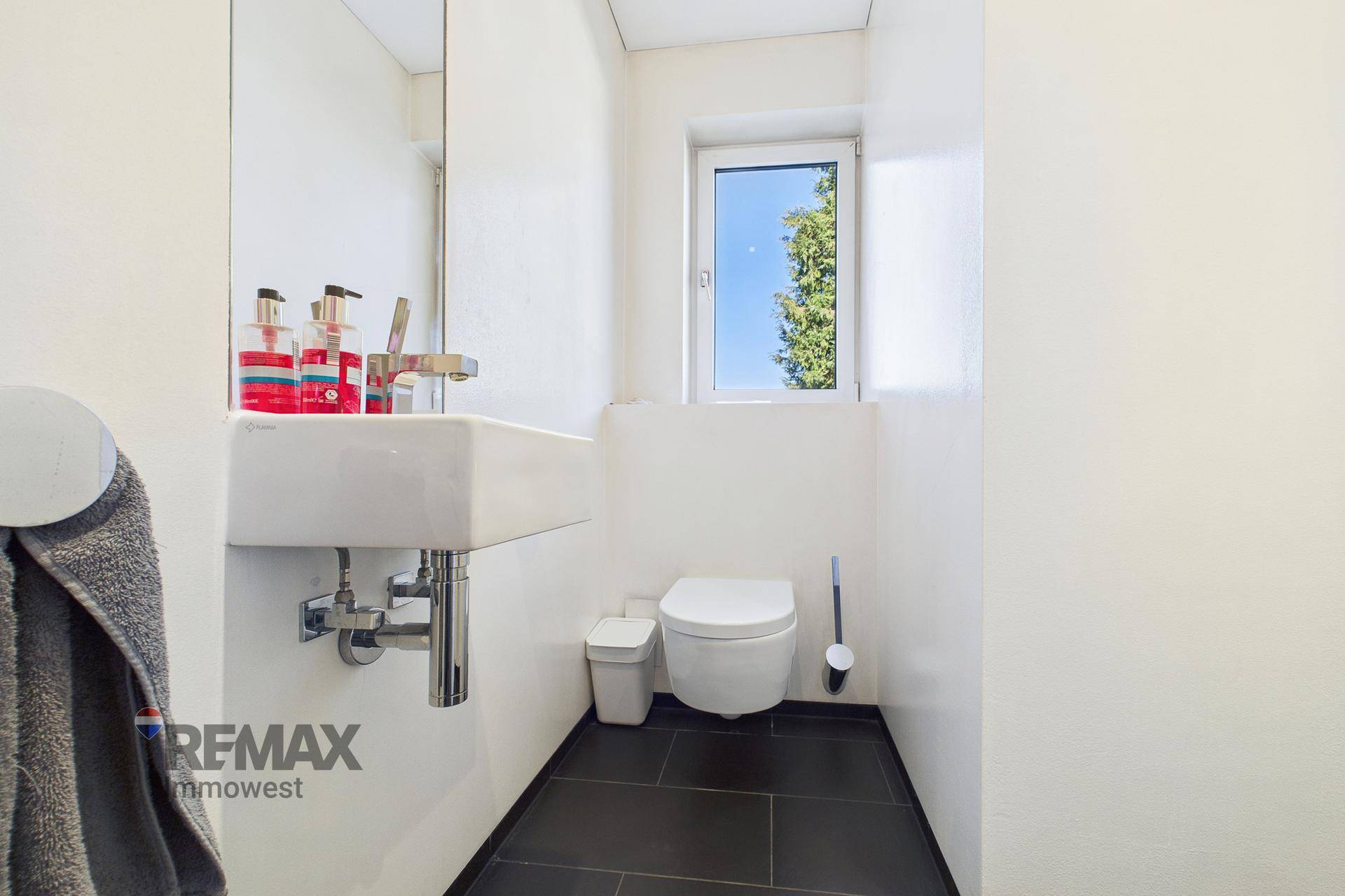 Modernes Gäste-WC mit wandmontierter Toilette und kleinem Fenster.