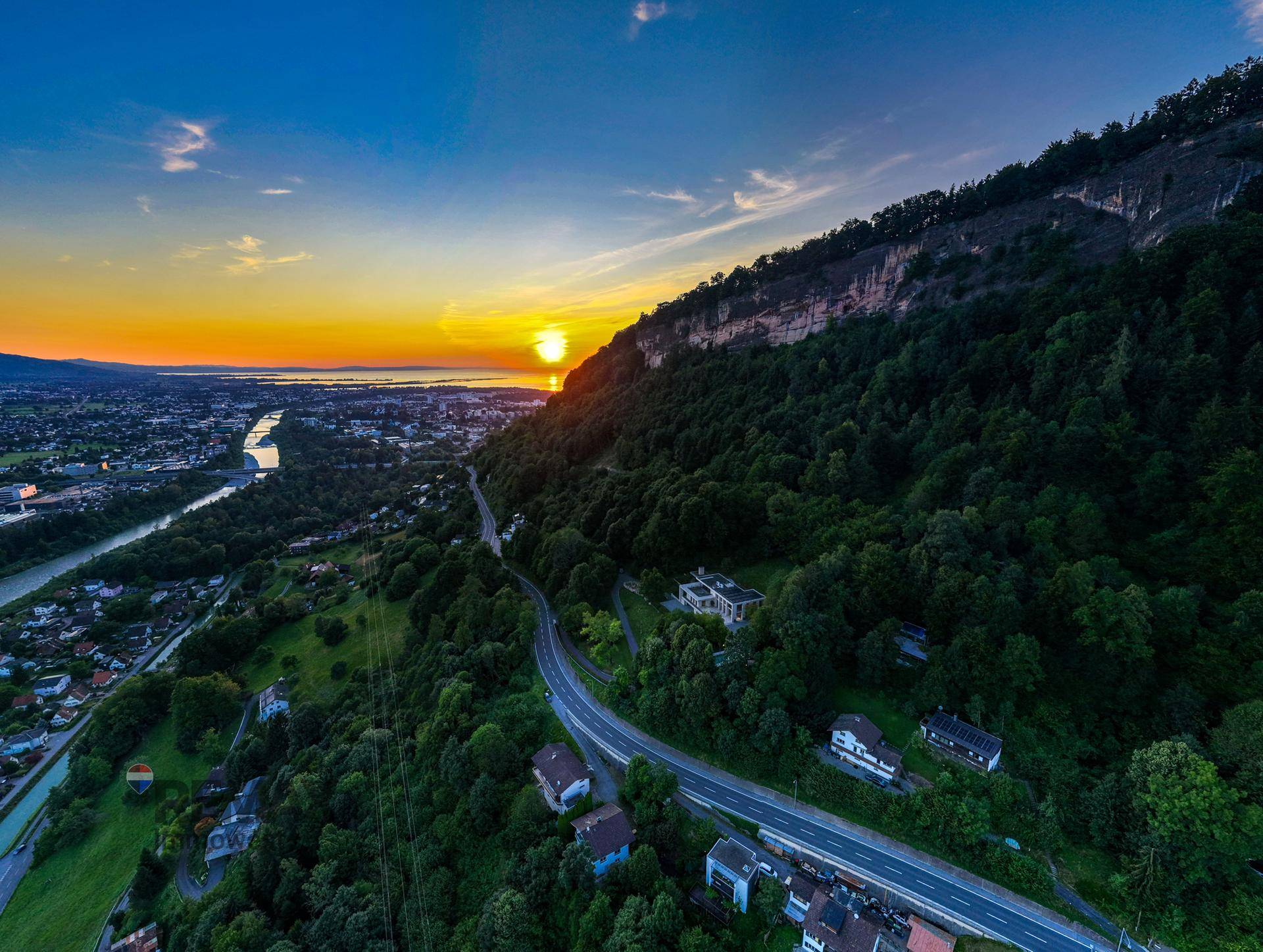 Spektakulärer Sonnenuntergang über der Berglandschaft, mit Blick auf die Villa und die umliegende Natur.