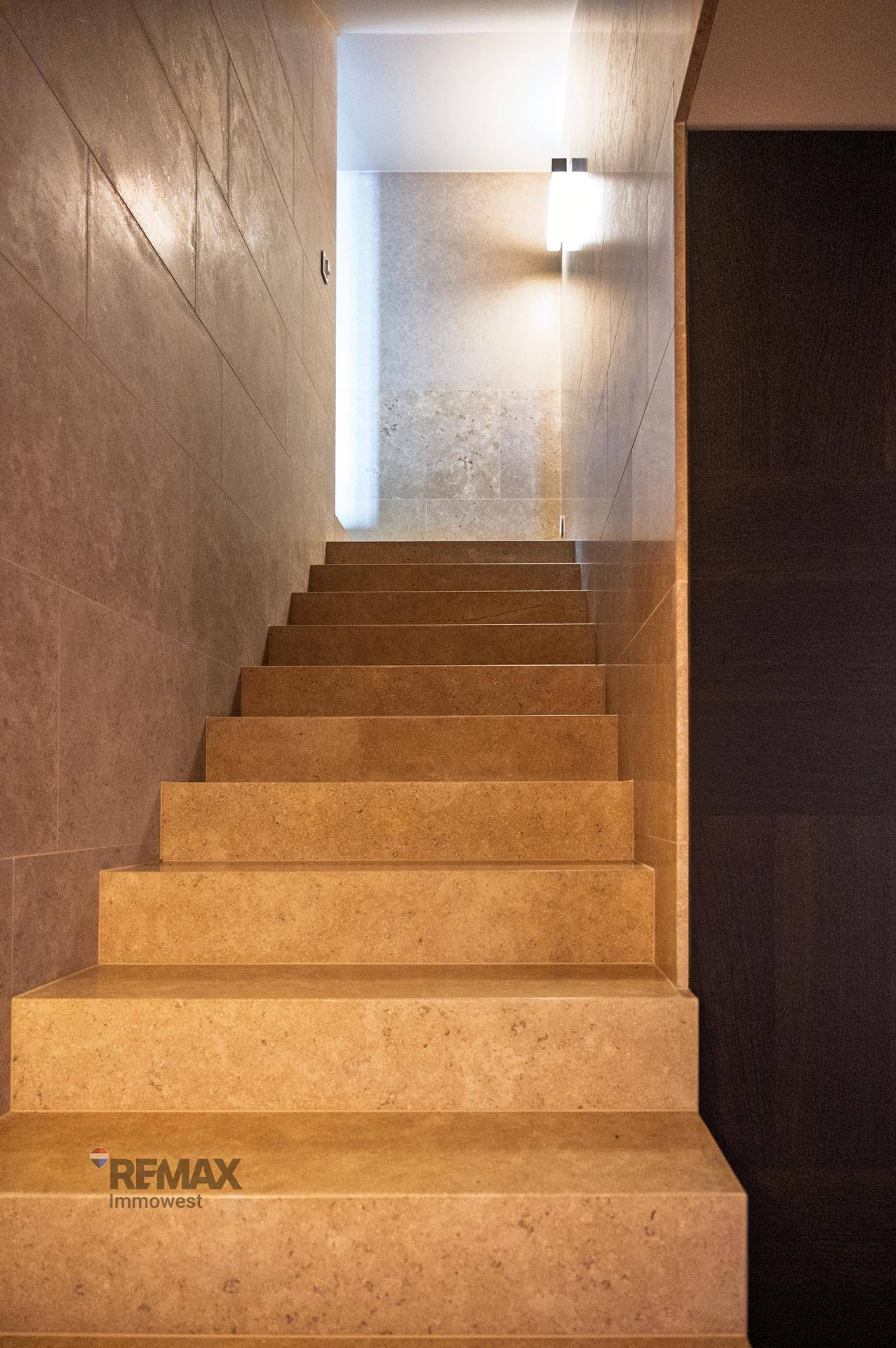 Elegante Steintreppe mit indirekter Beleuchtung, die verschiedene Ebenen des Hauses verbindet.