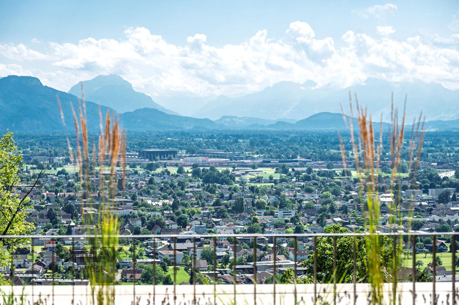 Panoramablick über die Stadt und die umliegende Berglandschaft an einem sonnigen Tag.