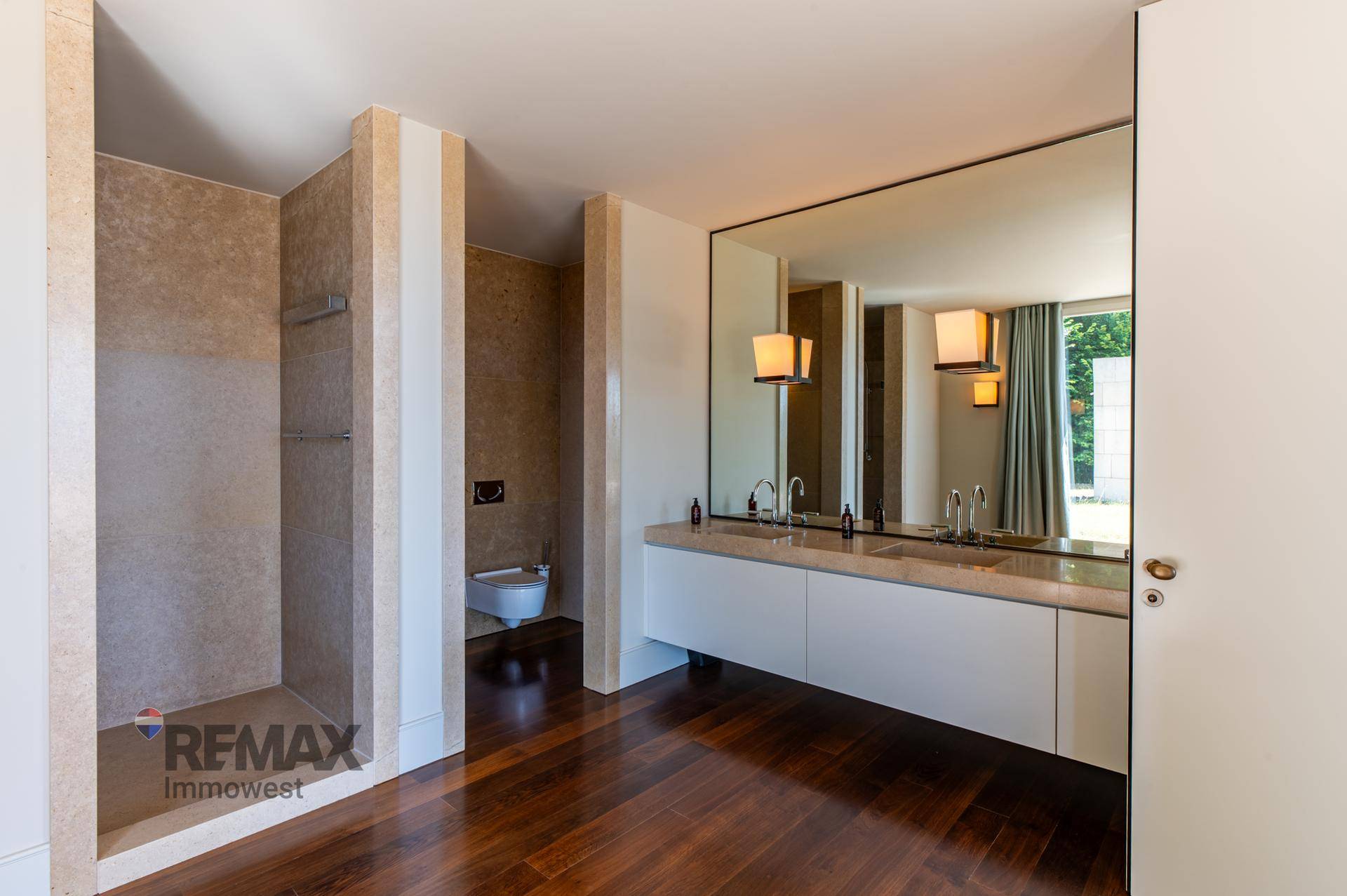 Geräumiges Badezimmer mit Doppelwaschbecken, Dusche und großem Spiegel.