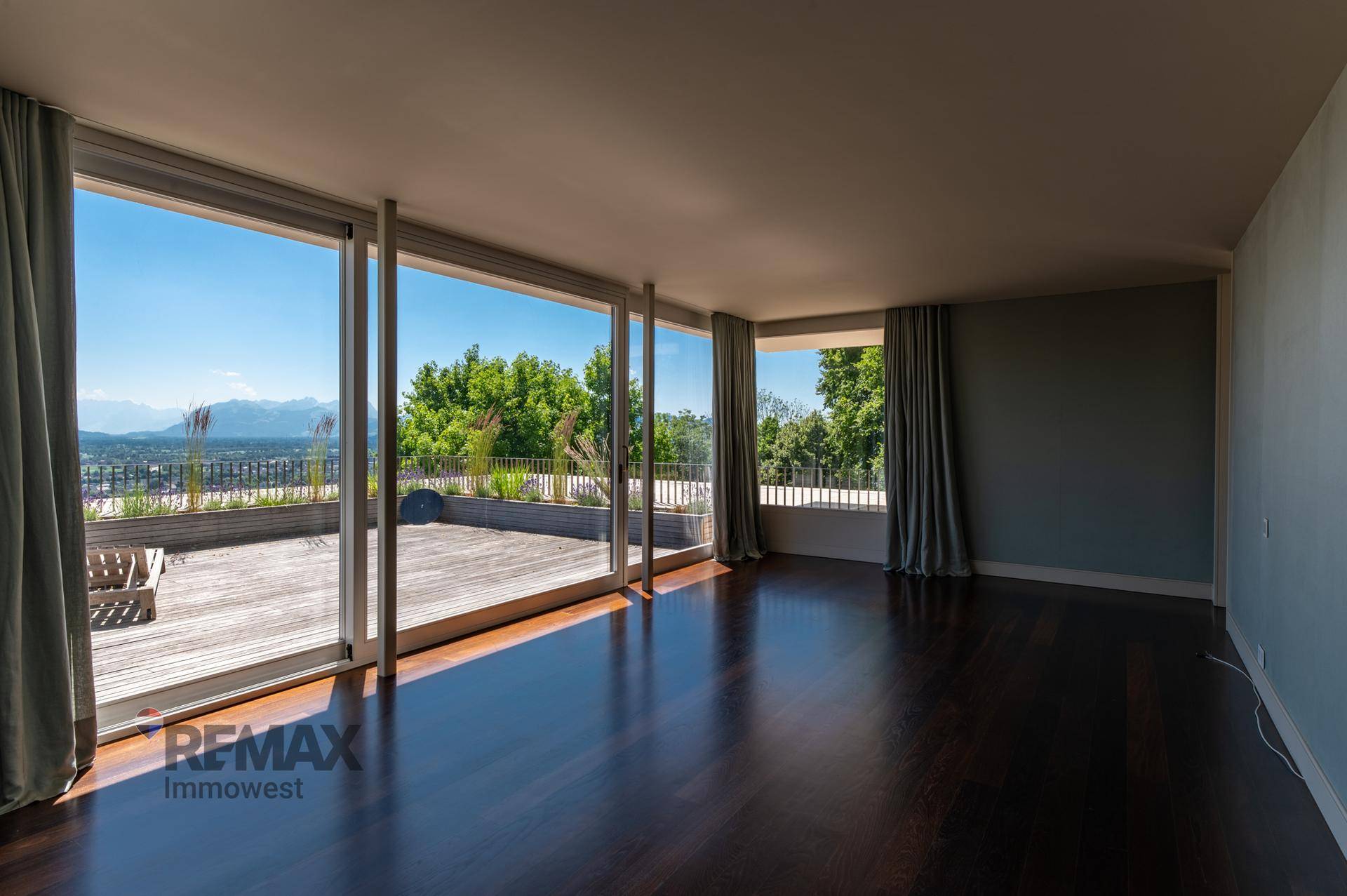 Helles Wohnzimmer mit dunklem Holzboden und raumhohen Fenstern mit Panoramablick.