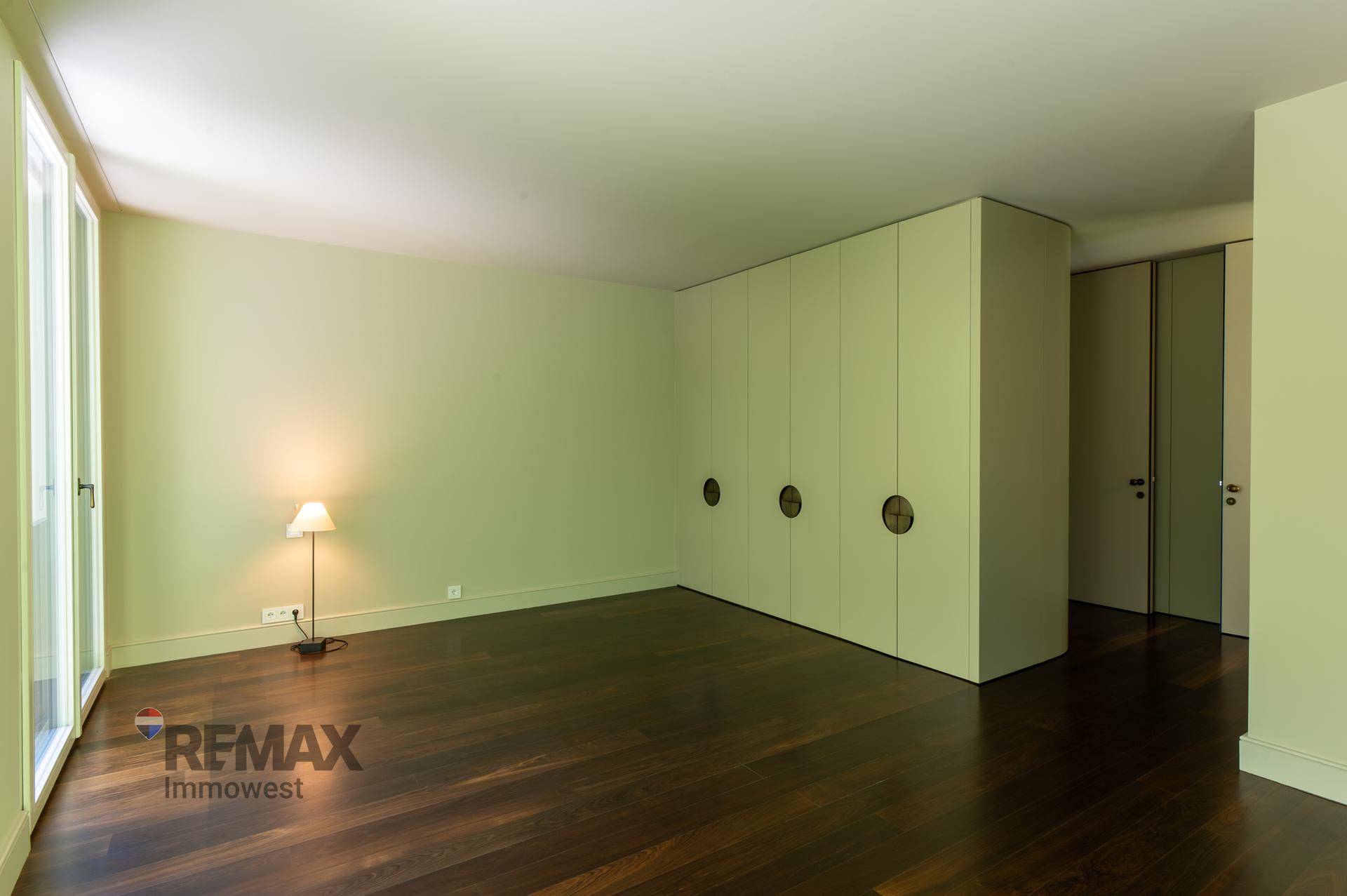 Geräumiges Schlafzimmer mit Einbauschränken und dunklem Holzboden.