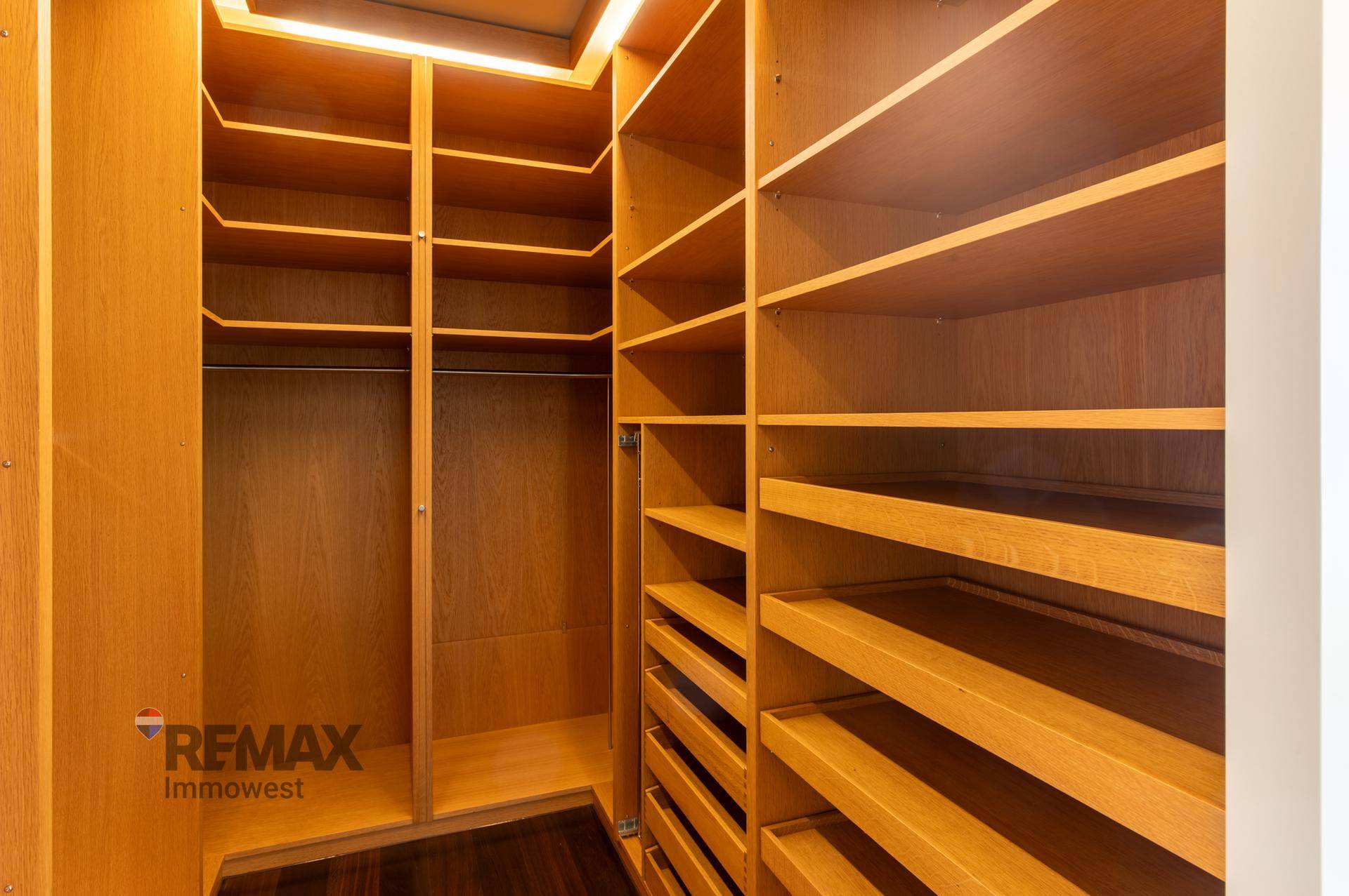 Begehbarer Kleiderschrank mit vielen Holzregalen und Stauraum.