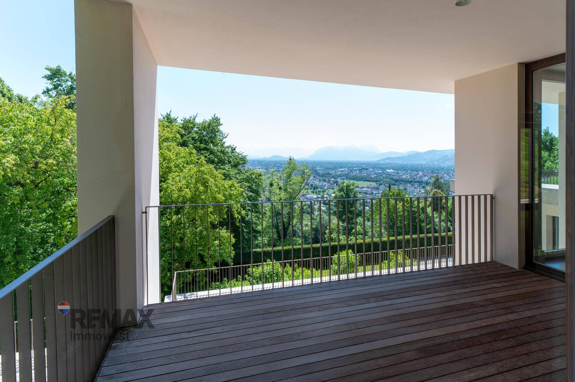 Großer Balkon mit Holzboden und weitem Blick über die grüne Landschaft.