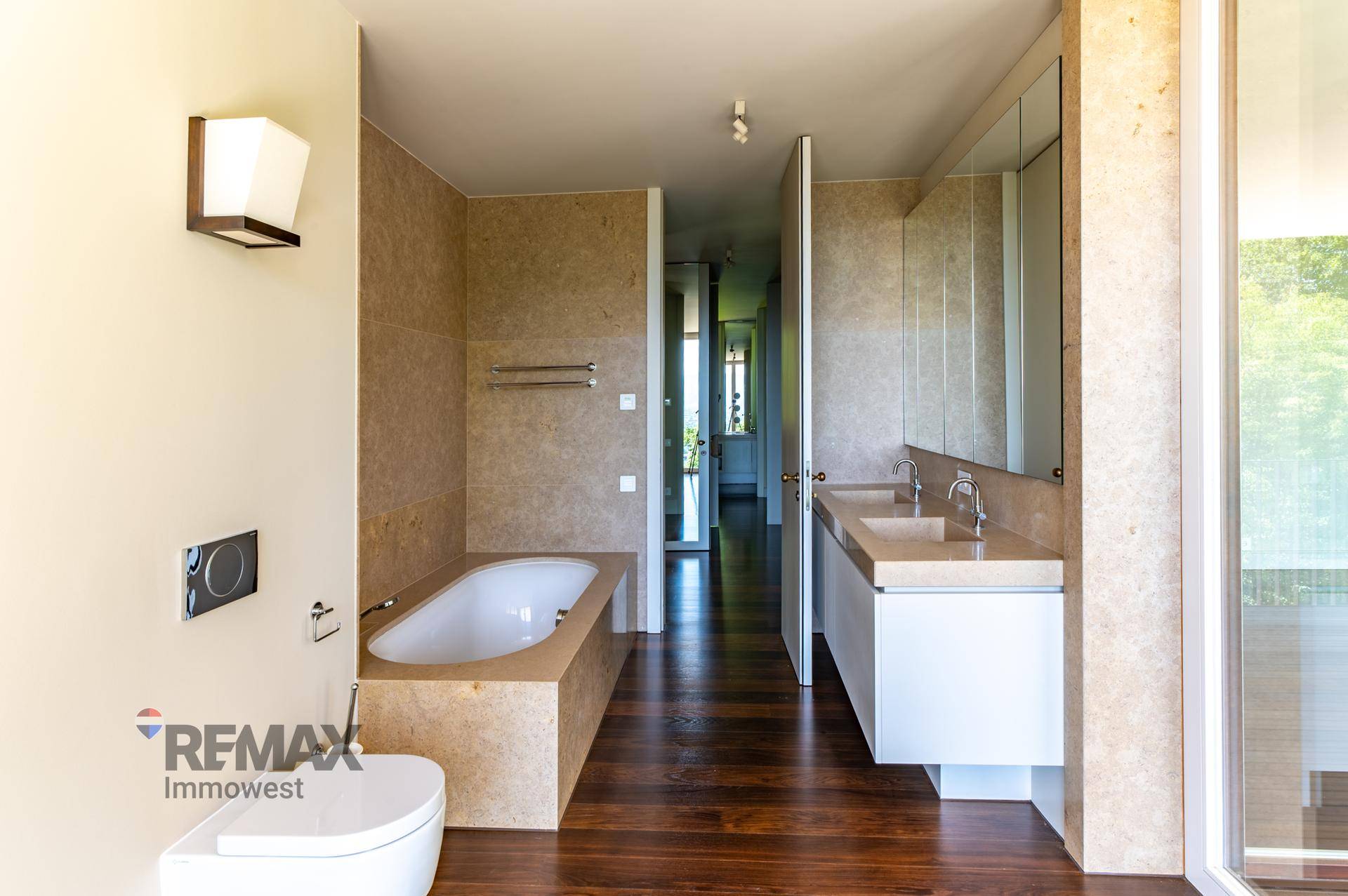 Modernes Badezimmer mit Badewanne, Doppelwaschbecken und Holzboden.