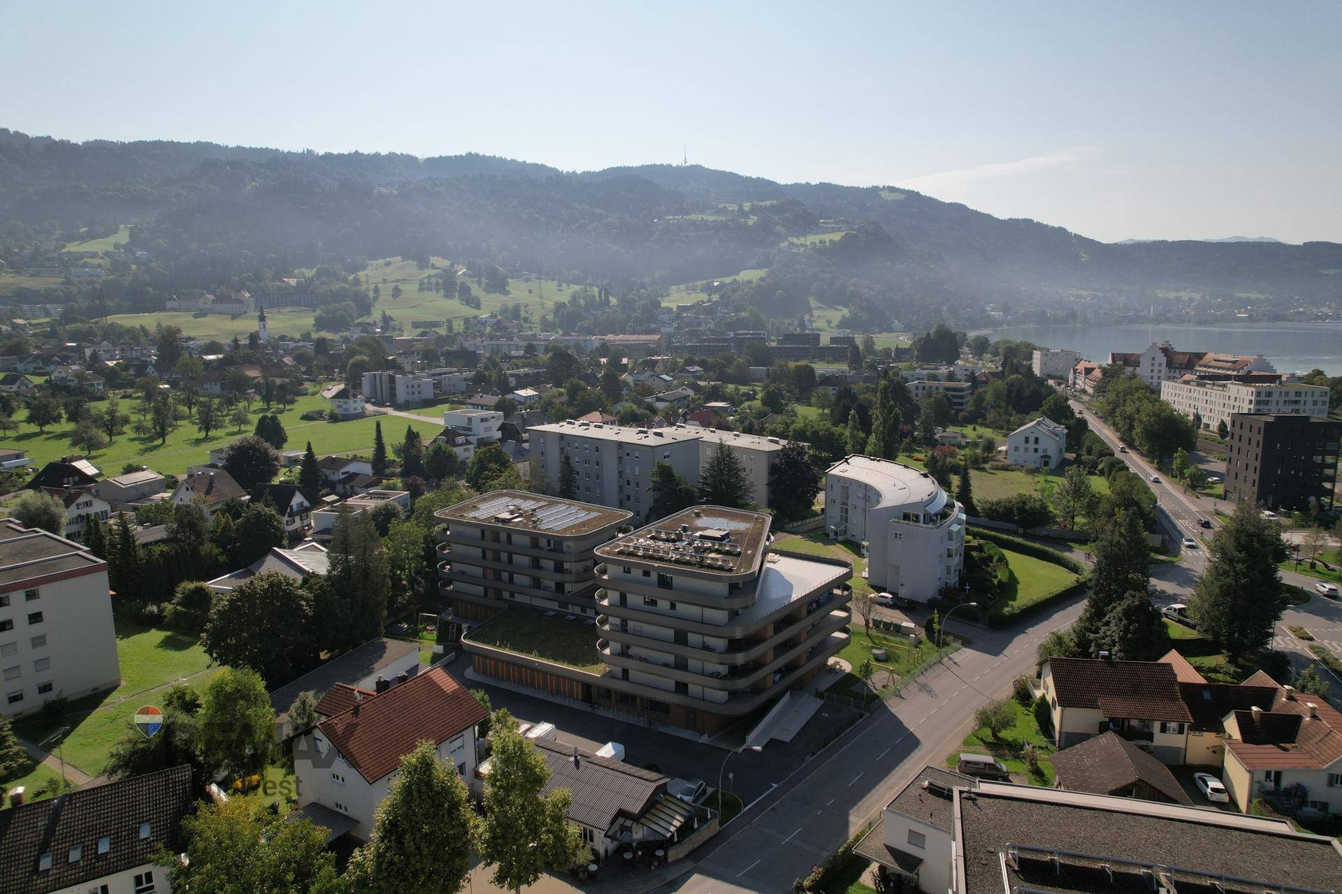 Weitläufige Luftaufnahme einer modernen Wohnanlage mit Gründächern, Solaranlagen und grüner Umgebung.