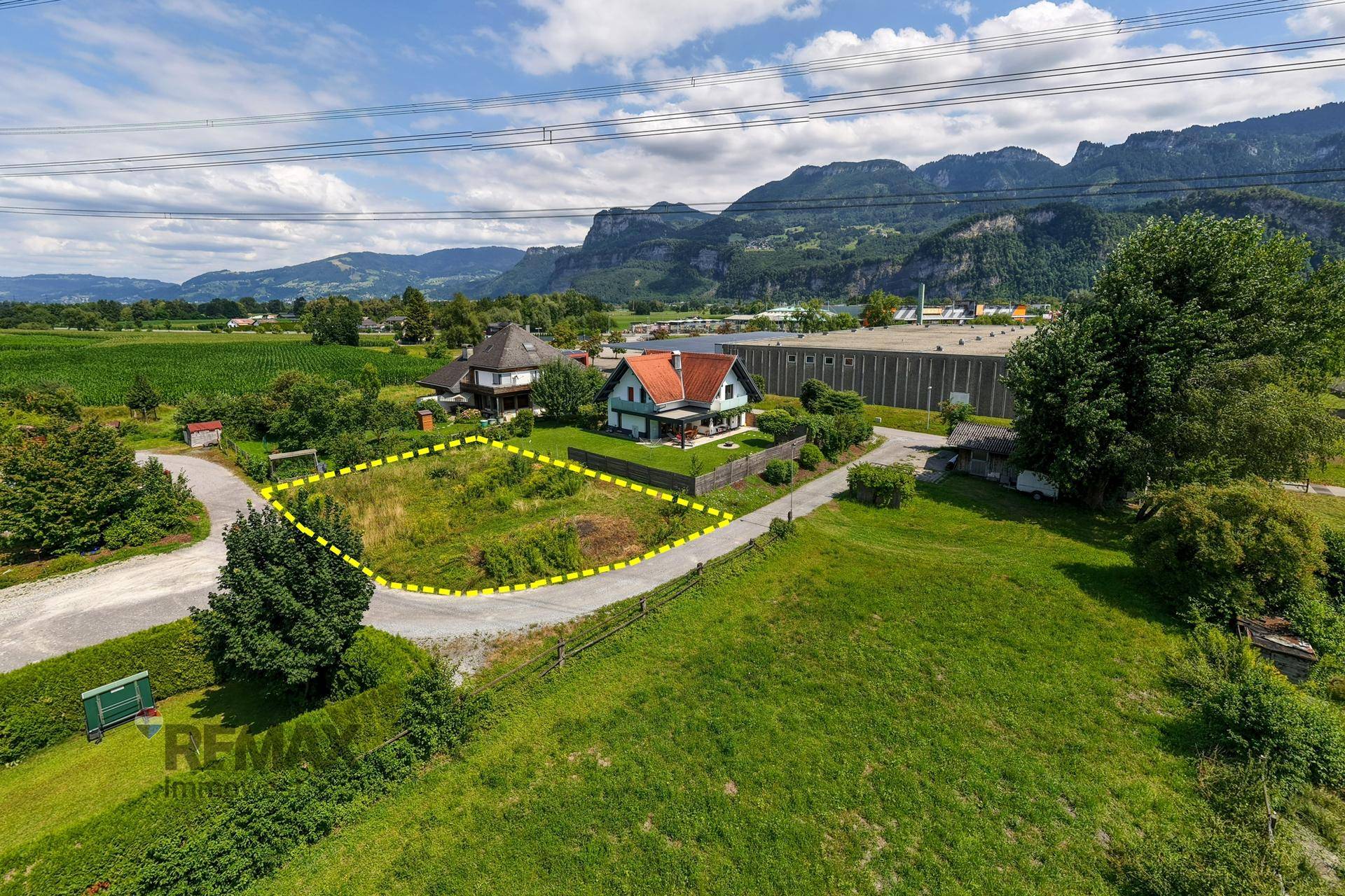 Weitläufige Luftaufnahme eines Grundstücks mit Bergblick, umgeben von Feldern und ländlicher Bebauung.