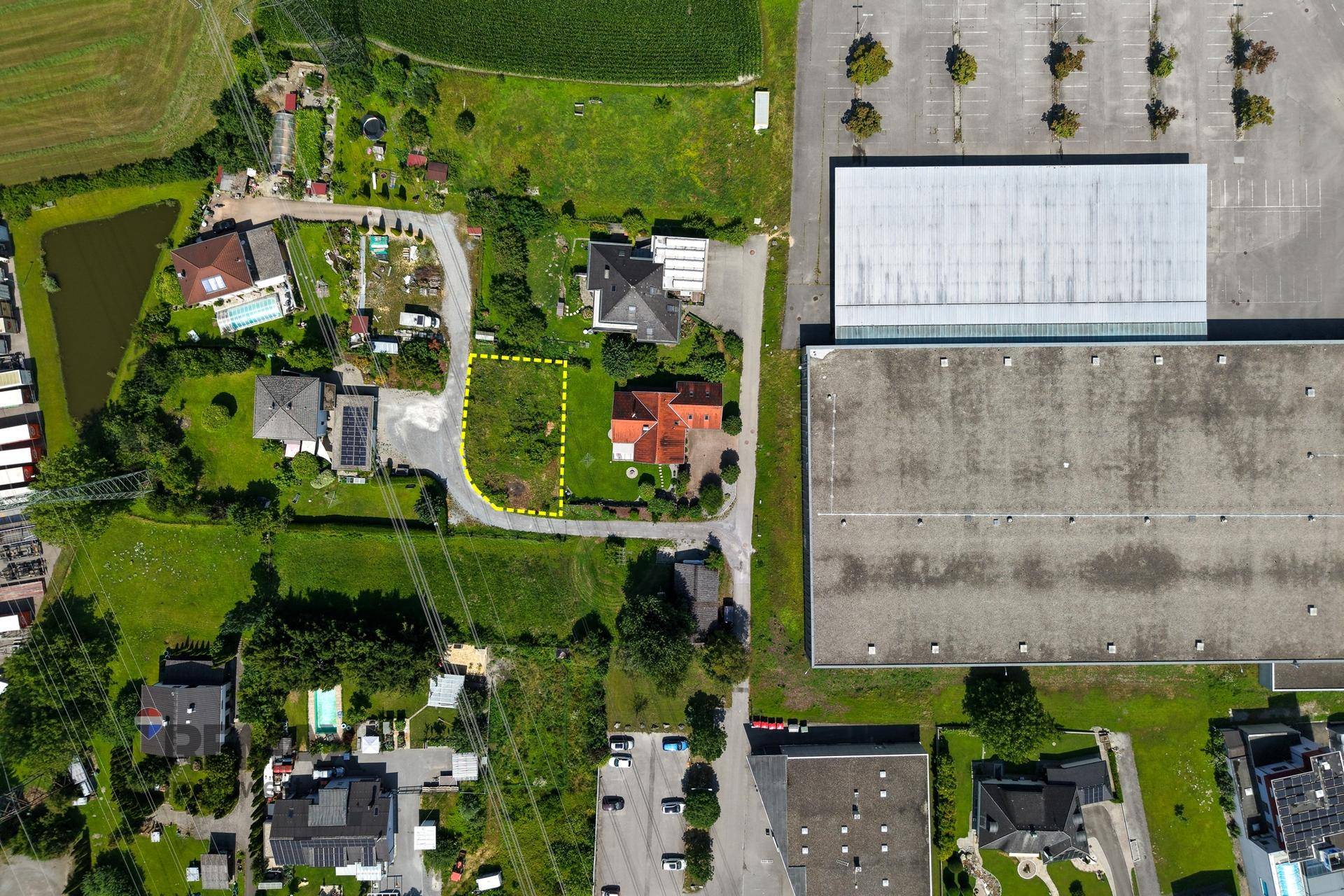 Übersichtliche Luftaufnahme eines Baugrundstücks in einer Mischzone mit Wohn- und Gewerbegebäuden.