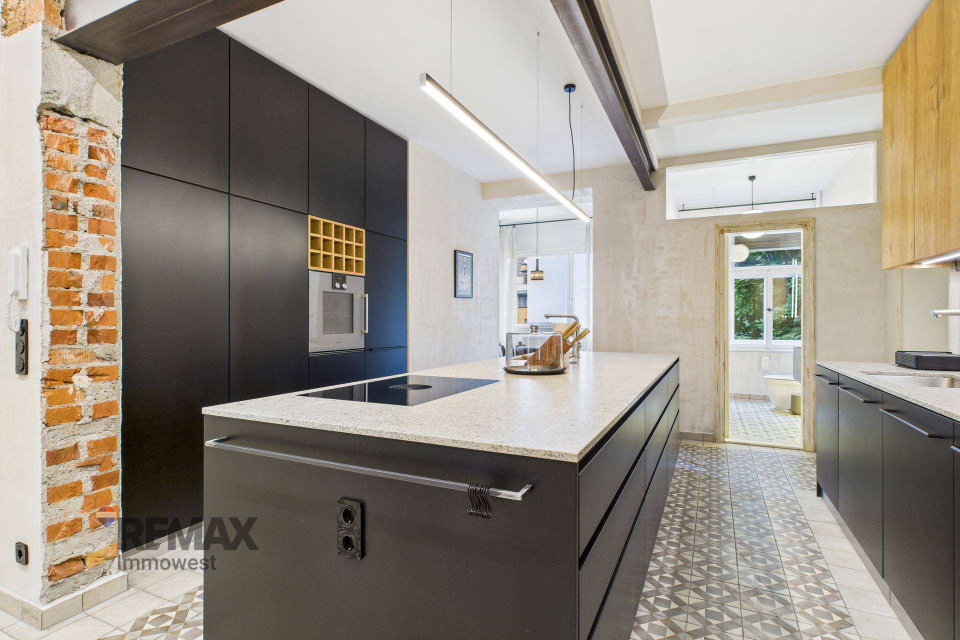 Moderne Küche mit schwarzem Design, Kücheninsel und freigelegten Ziegelwänden.