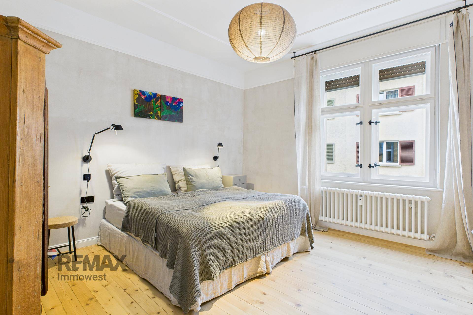 Helles Schlafzimmer mit Holzboden, großem Fenster und einem bequemen Doppelbett.
