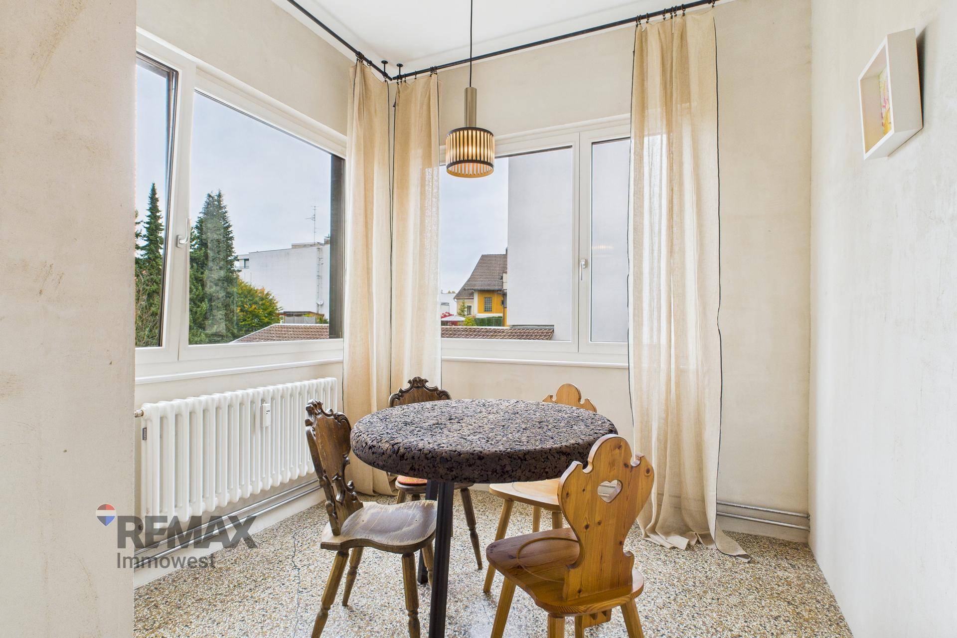 Kleiner Essbereich mit rustikalen Holzstühlen und einem Fenster mit Blick ins Grüne.
