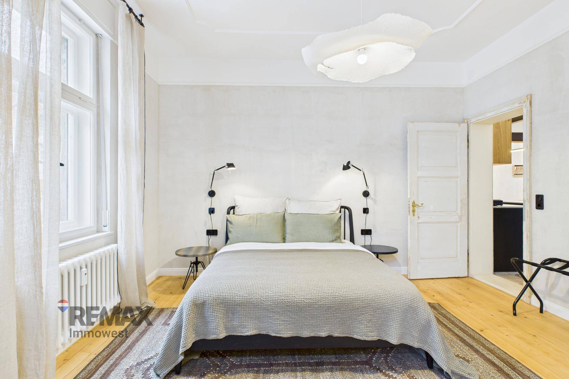 Schlafzimmer mit Holzboden, Doppelbett und moderner Beleuchtung.