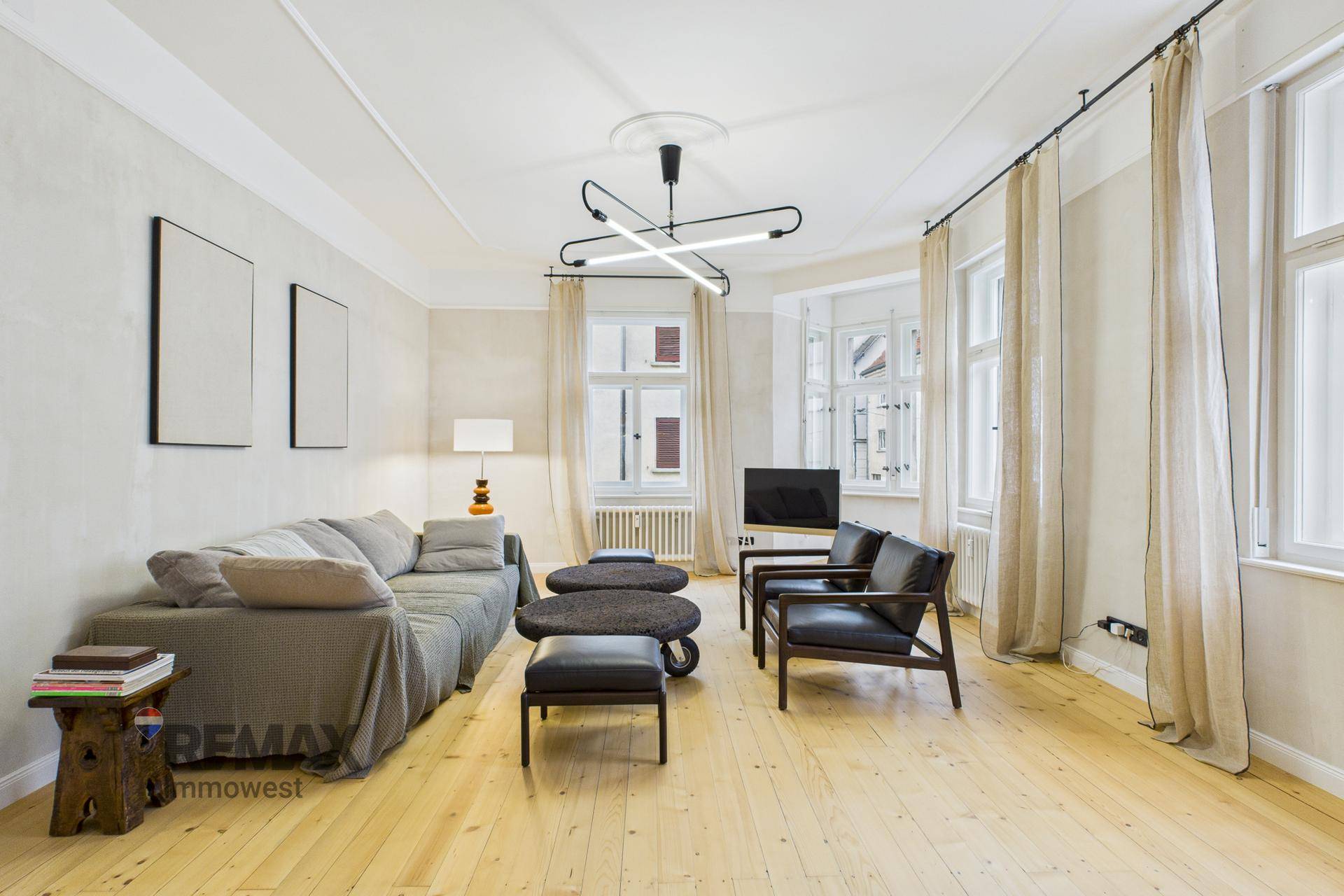 Gemütliches Wohnzimmer mit Holzboden, großen Fenstern und moderner Einrichtung.