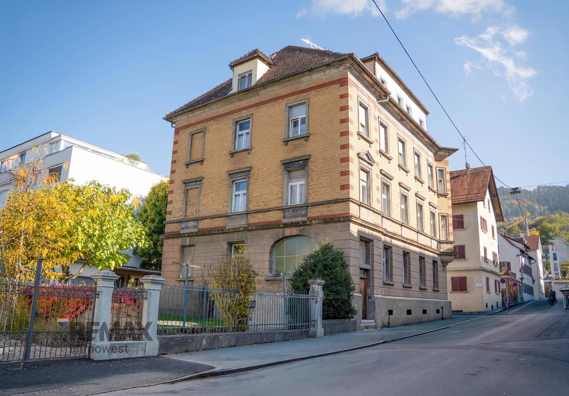 Ansicht des gepflegten Gebäudes von der Straße mit Vorgarten und Zaun.